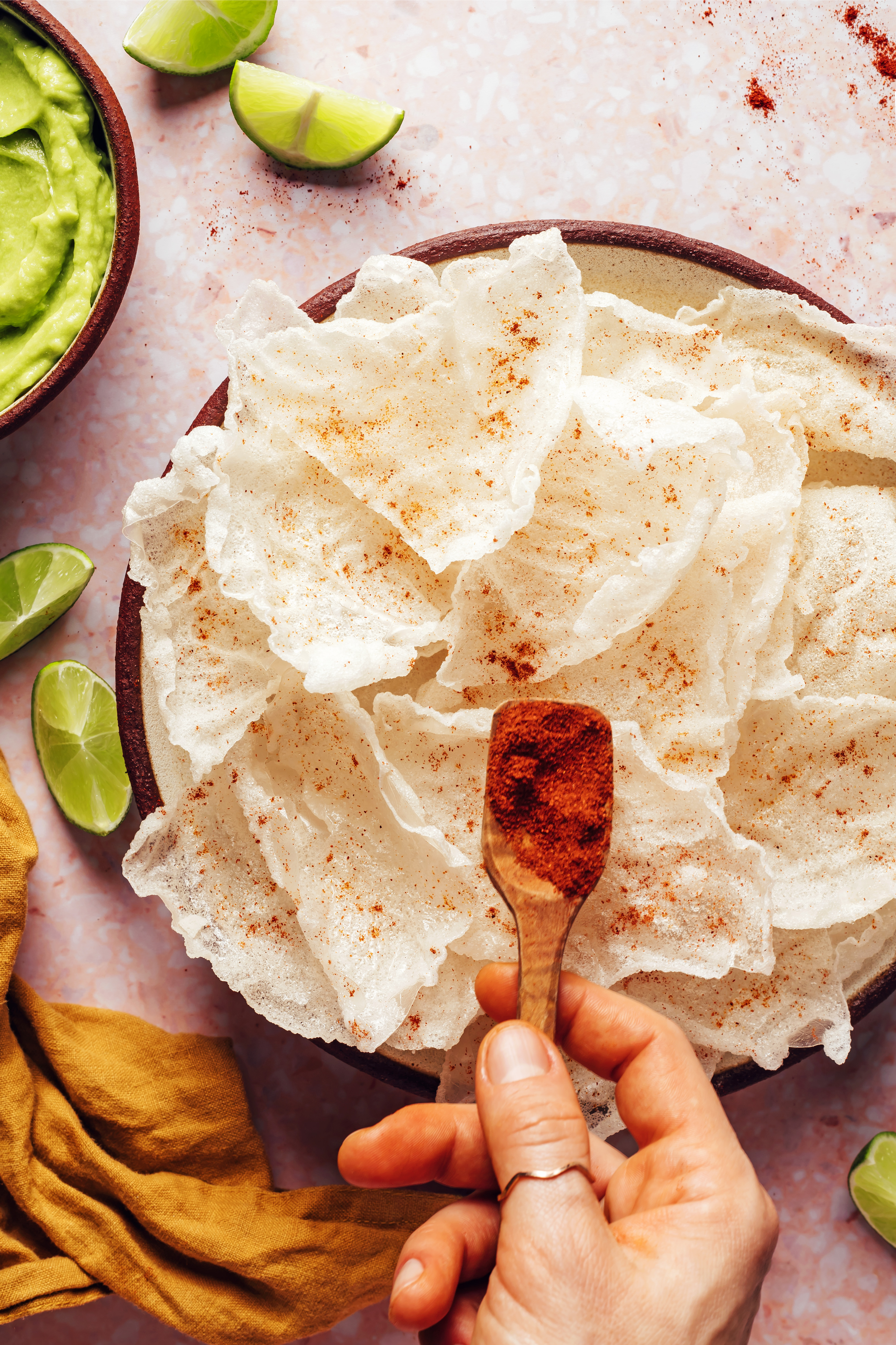 Sprinkling cayenne pepper over crispy homemade rice paper chips