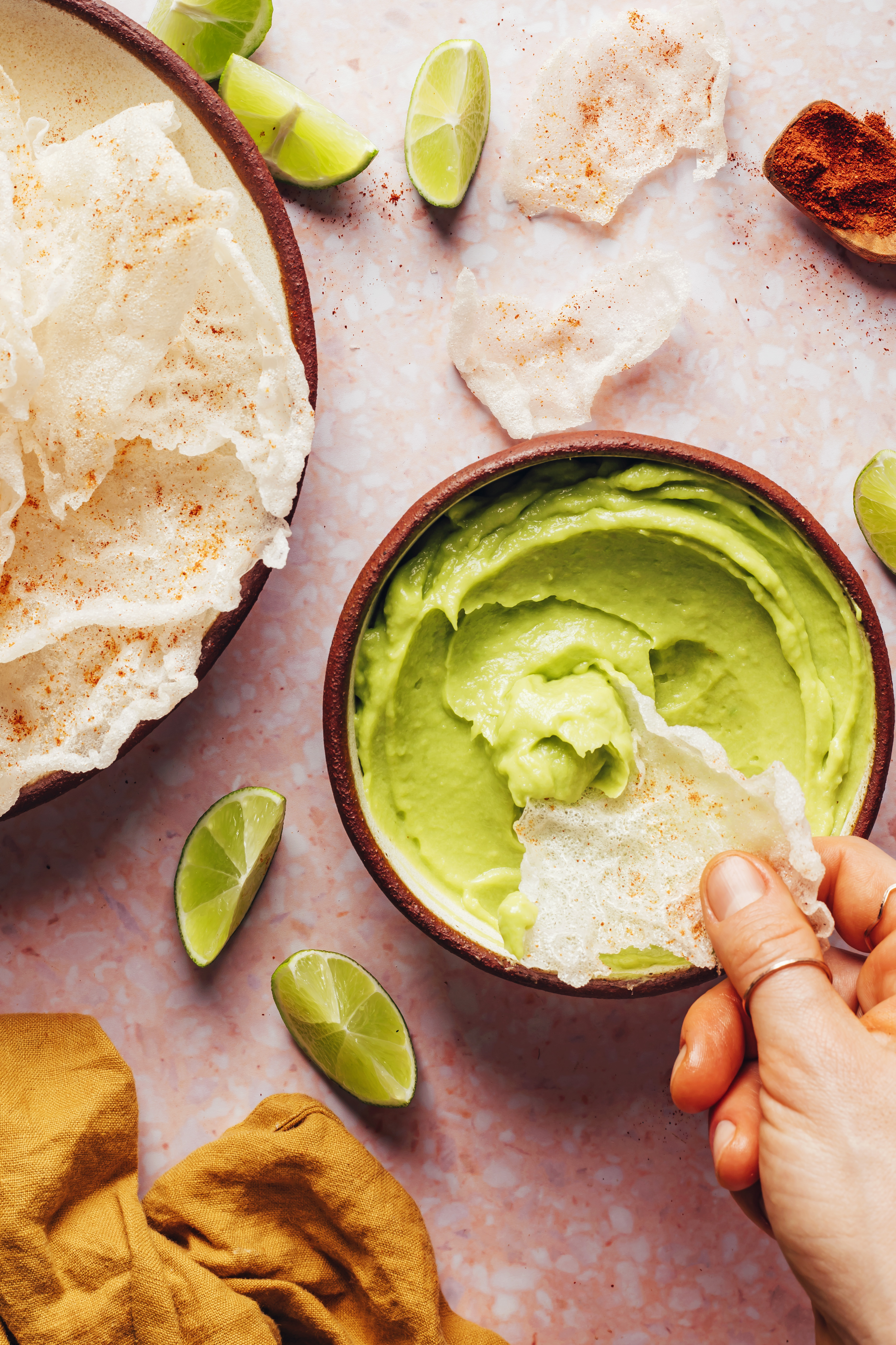 Dipping a rice paper chip into a creamy vegan avocado dip