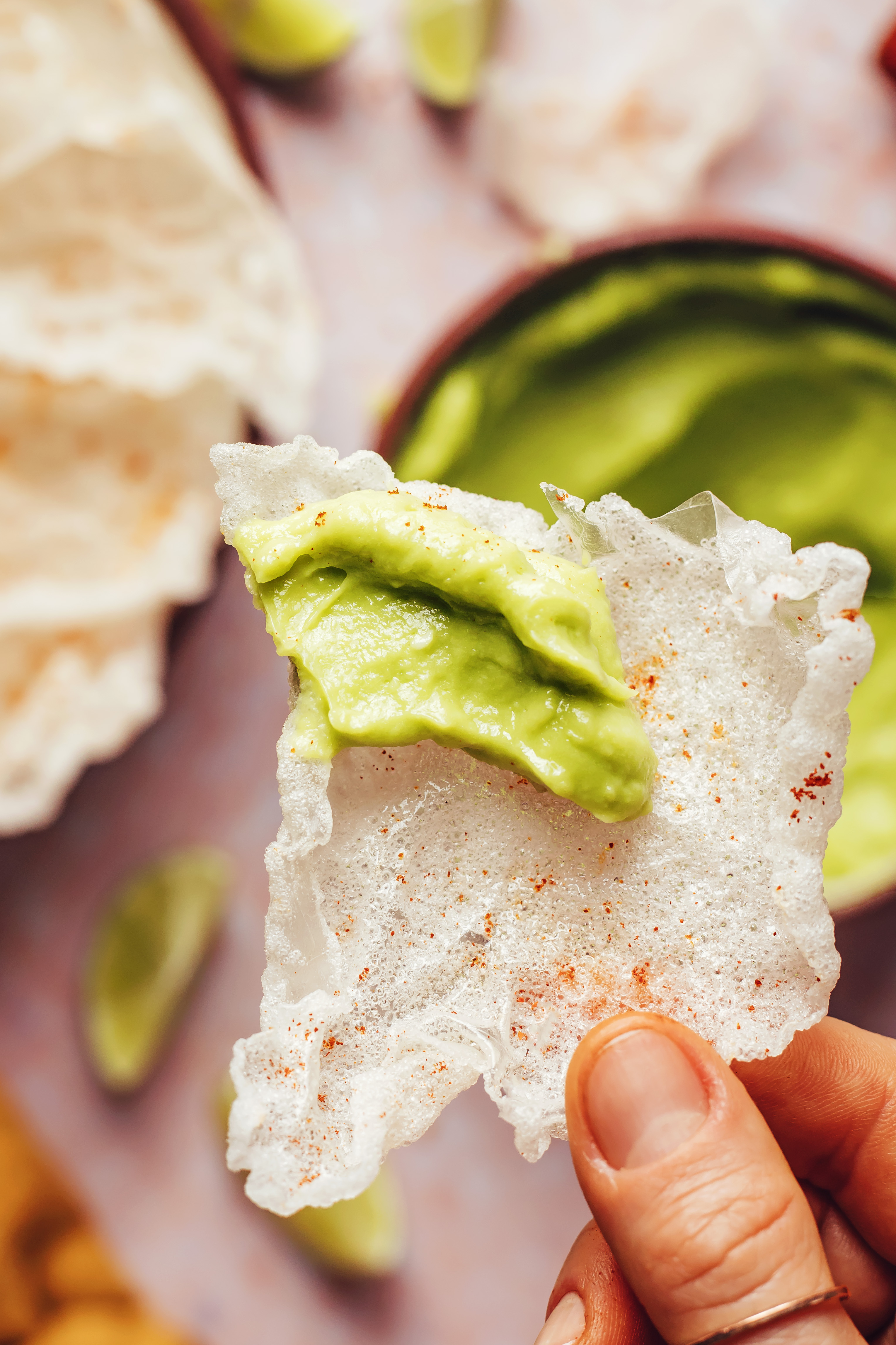 Close-up shot of fingers holding a sturdy chip with avocado dip