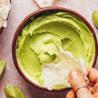 Dipping a chip into a bowl of avocado dip