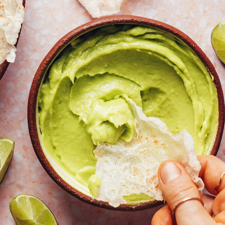 Dipping a chip into a bowl of avocado dip