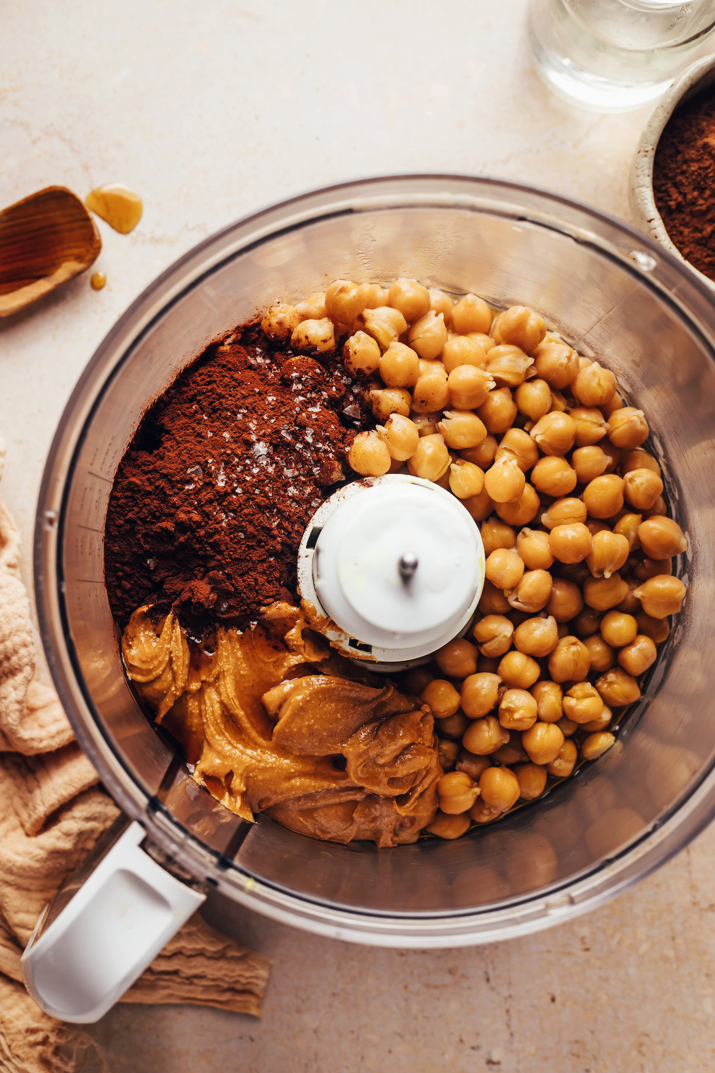 Food processor with chickpeas, cocoa powder, peanut butter, salt, and vanilla