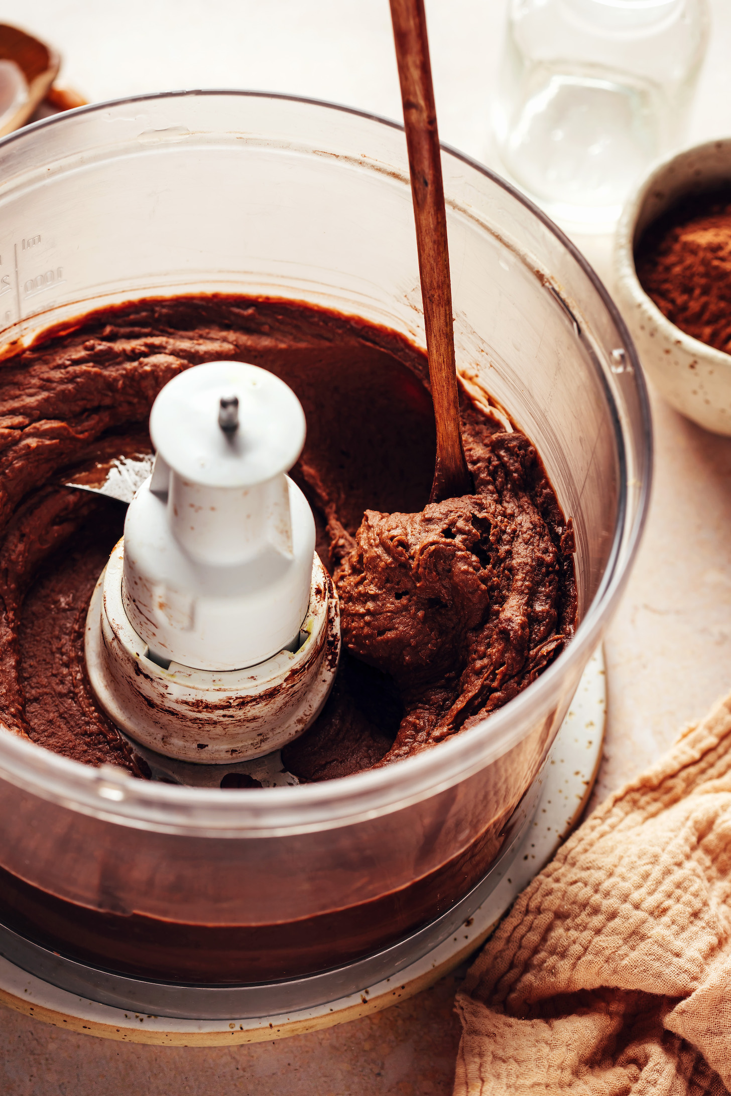 Small wood spoon in a food processor of creamy chocolate peanut butter hummus