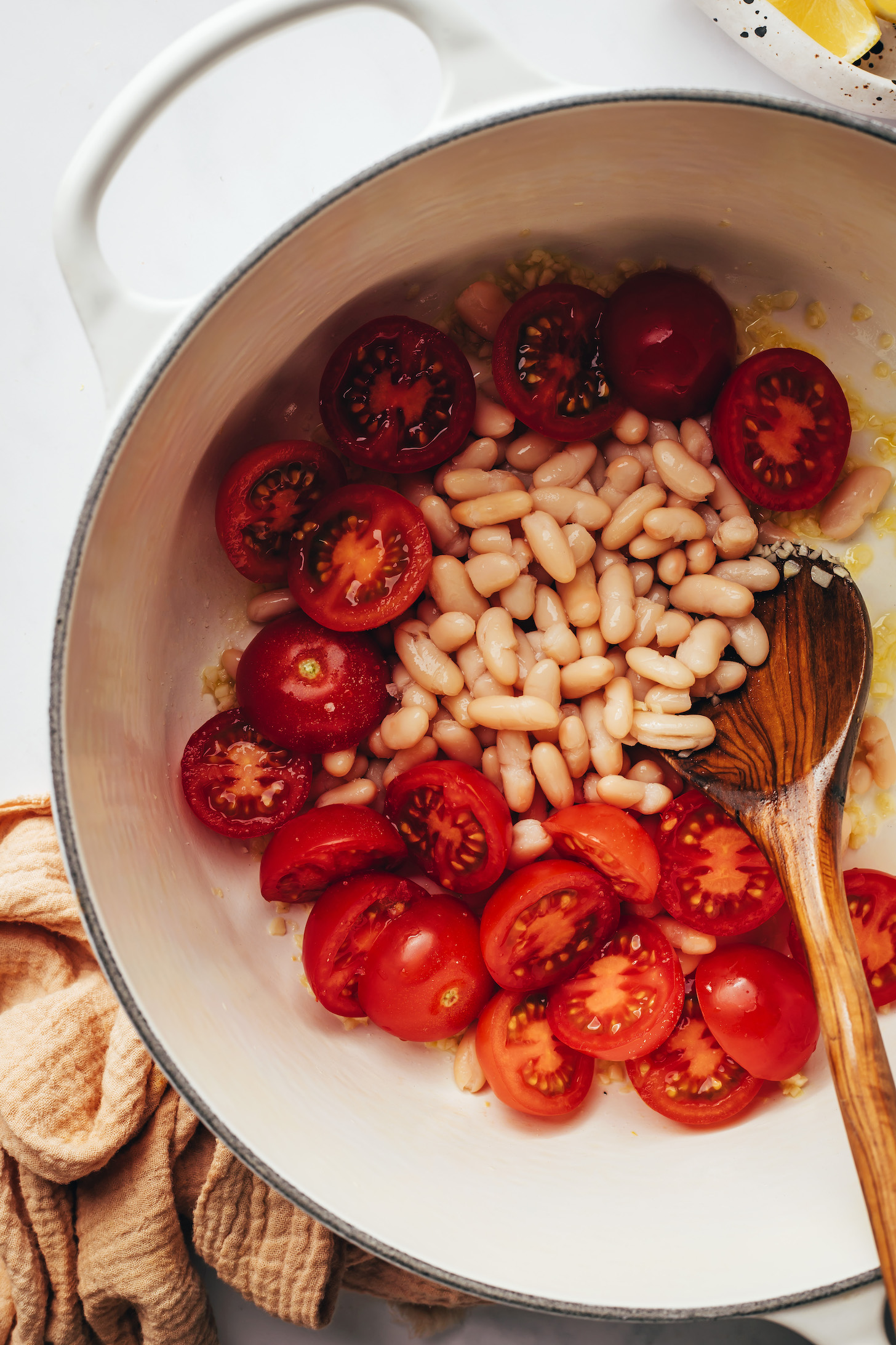 Sautéing garlic, lemon zest, white beans, and tomatoes