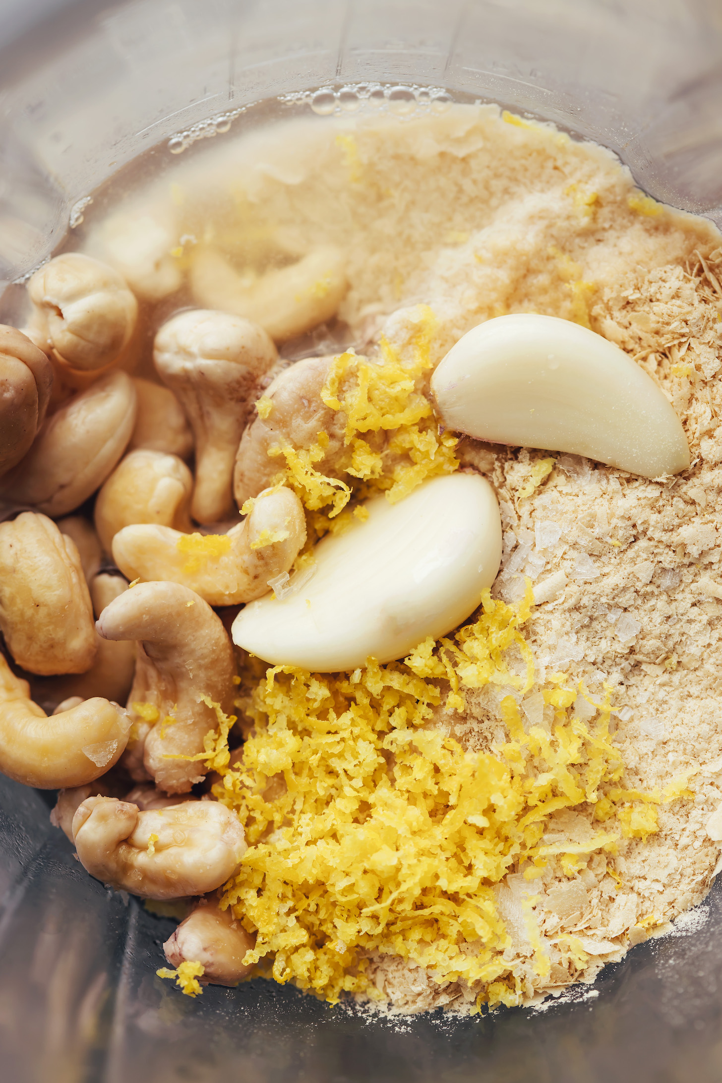Blender with cashews, garlic, lemon zest, salt, and nutritional yeast