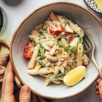 Bowl of vegan lemon garlic pasta with tomatoes and arugula