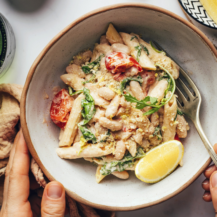 Bowl of vegan lemon garlic pasta with tomatoes and arugula