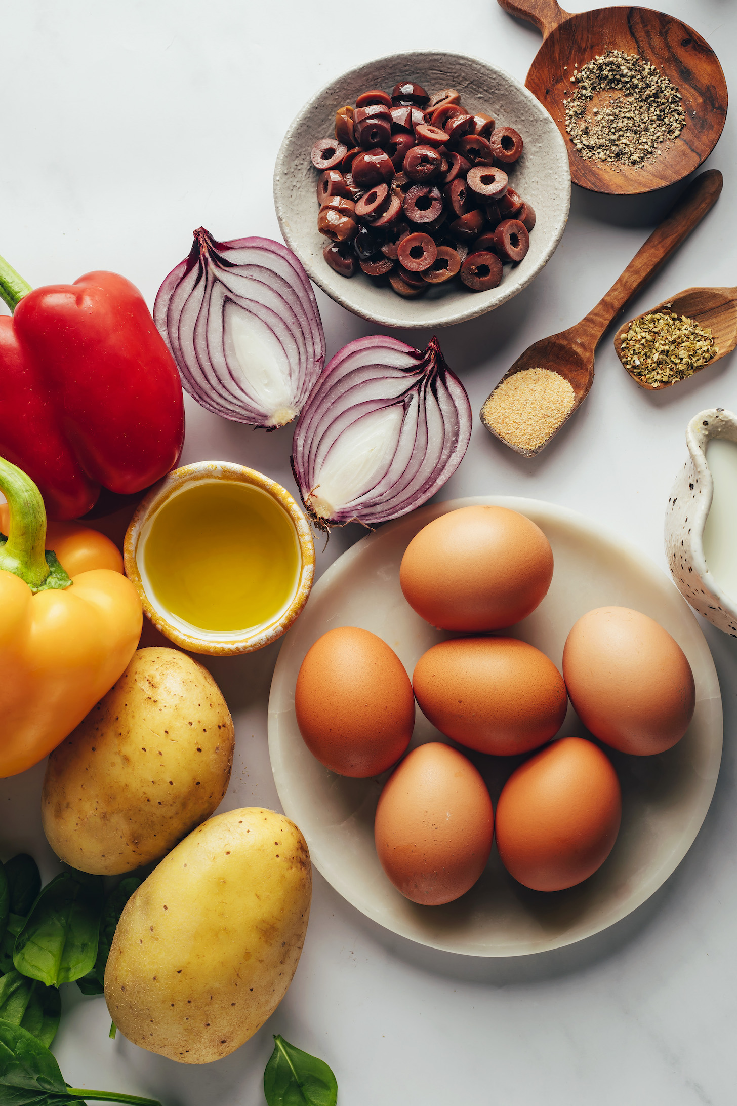 Spinach, potatoes, bell peppers, olive oil, onion, olives, black pepper, garlic powder, oregano, dairy-free milk, and eggs