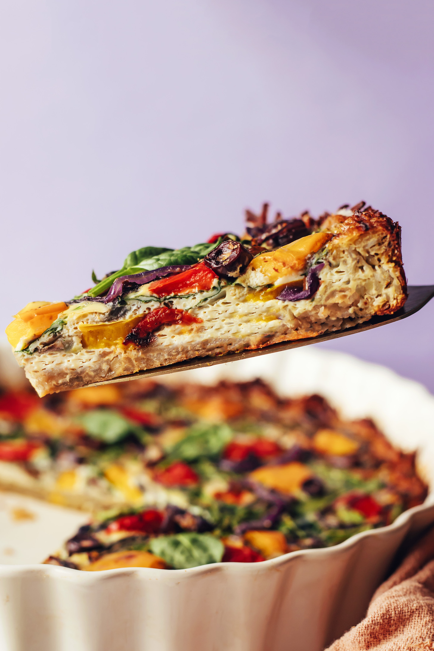 Holding up a slice of Mediterranean potato crust quiche