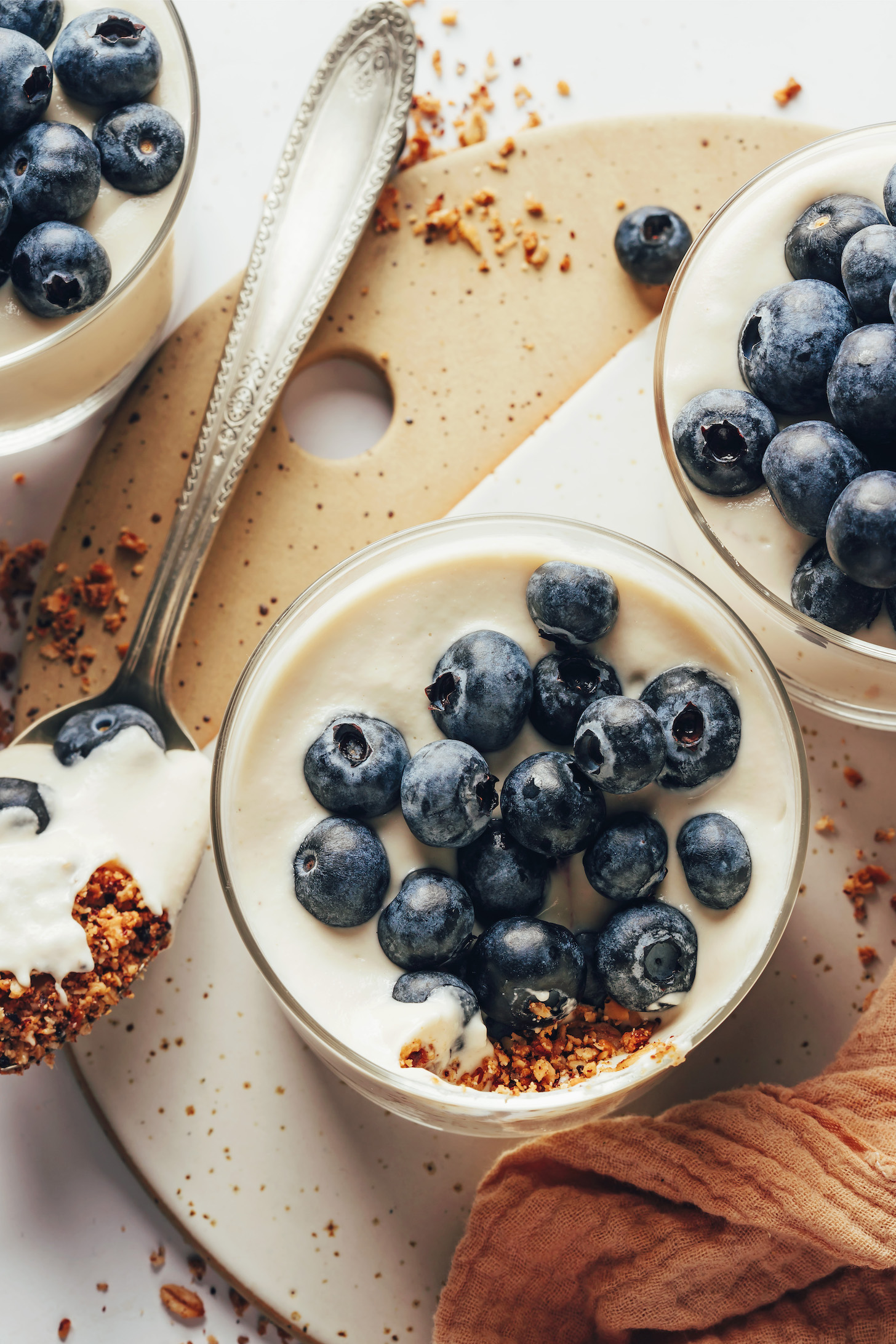 Overhead shot of three no-bake vegan cheesecake cups topped with fresh blueberries