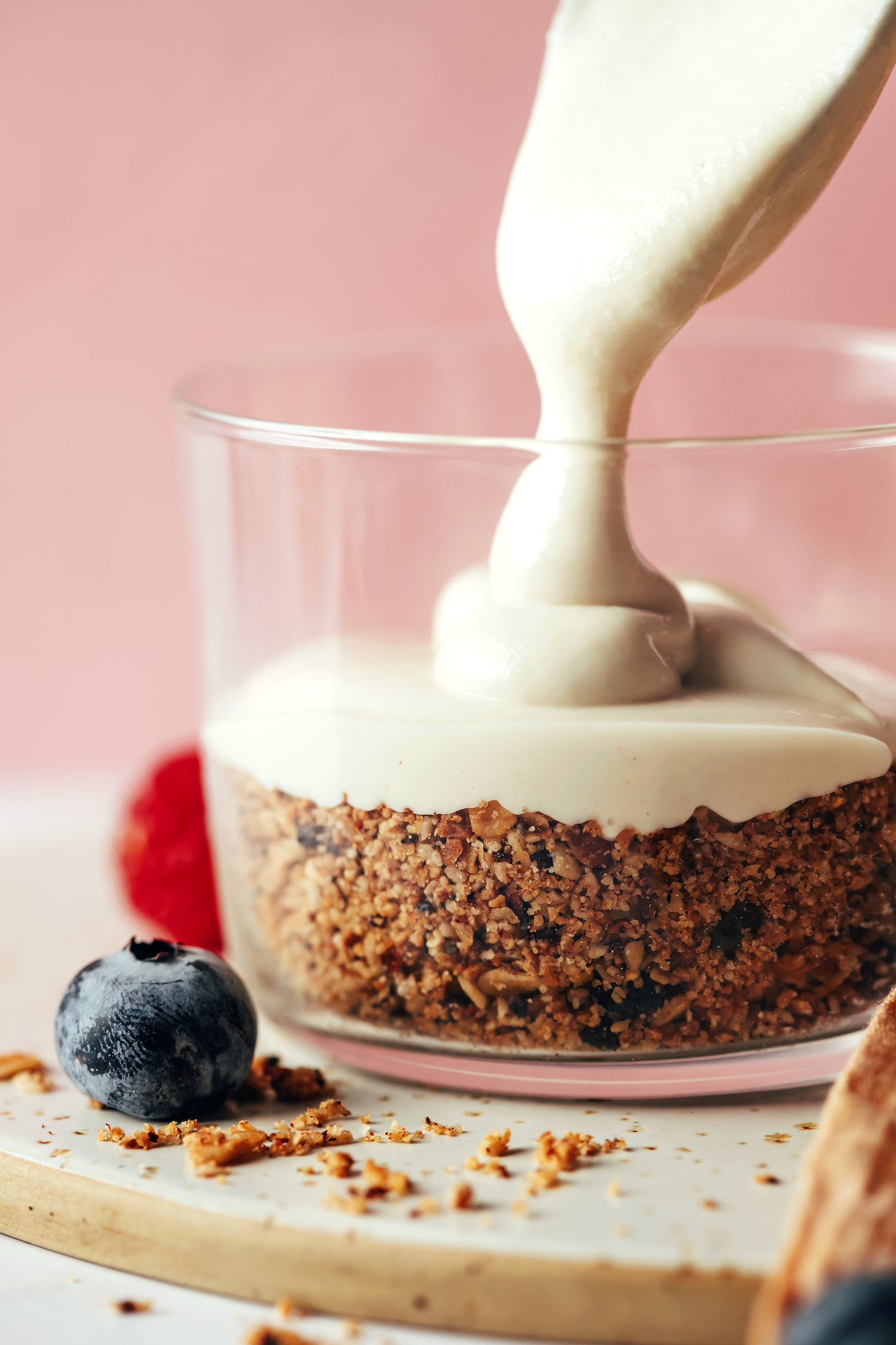Pouring a vegan cheesecake filling over crushed granola