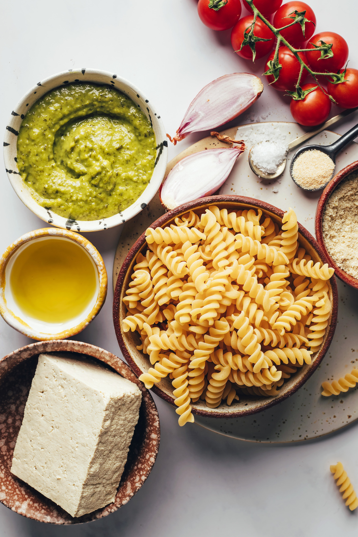 Pesto, shallot, cherry tomatoes, salt, garlic powder, nutritional yeast, pasta, tofu, and olive oil