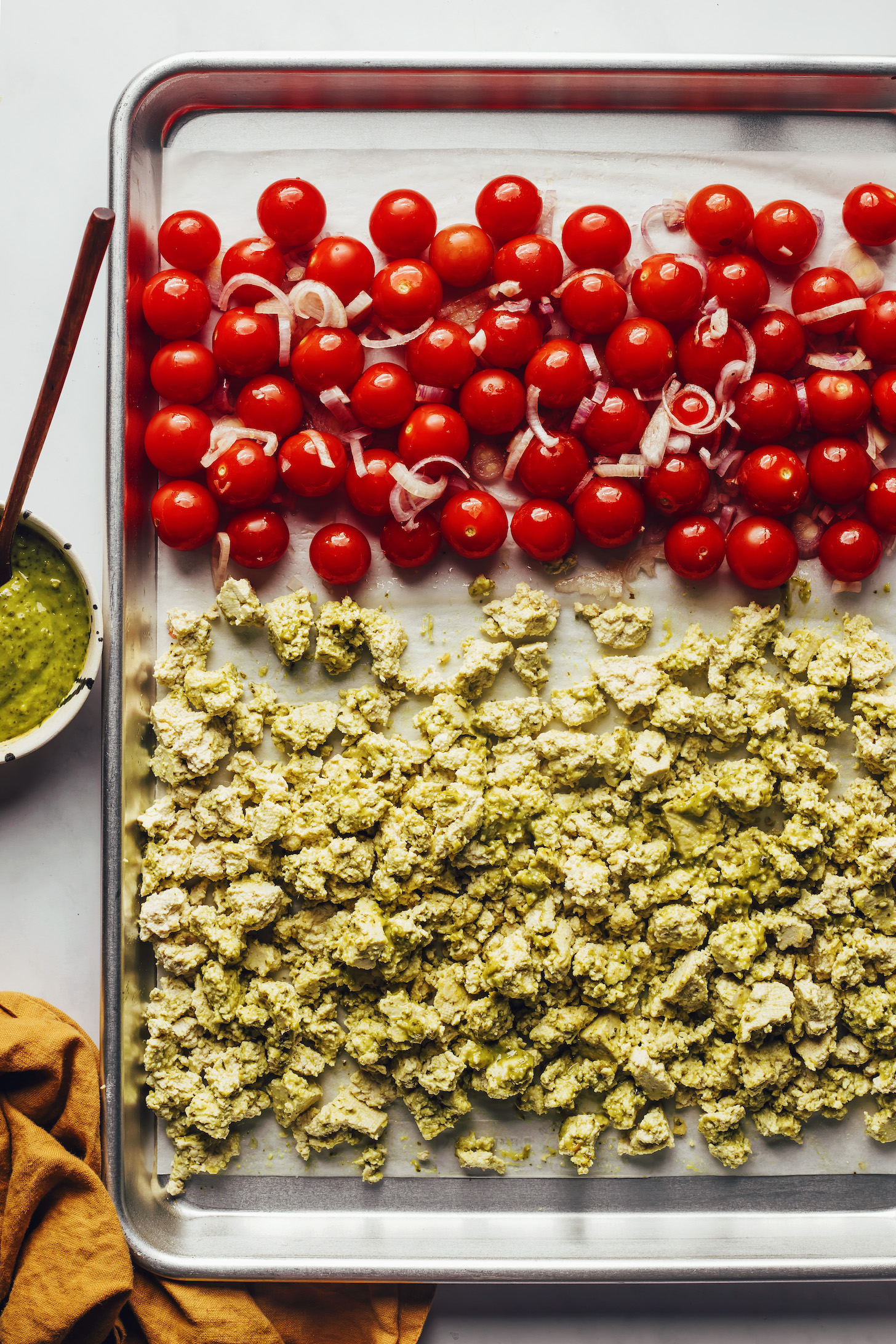Shallot, cherry tomatoes, and pesto tofu on a baking sheet