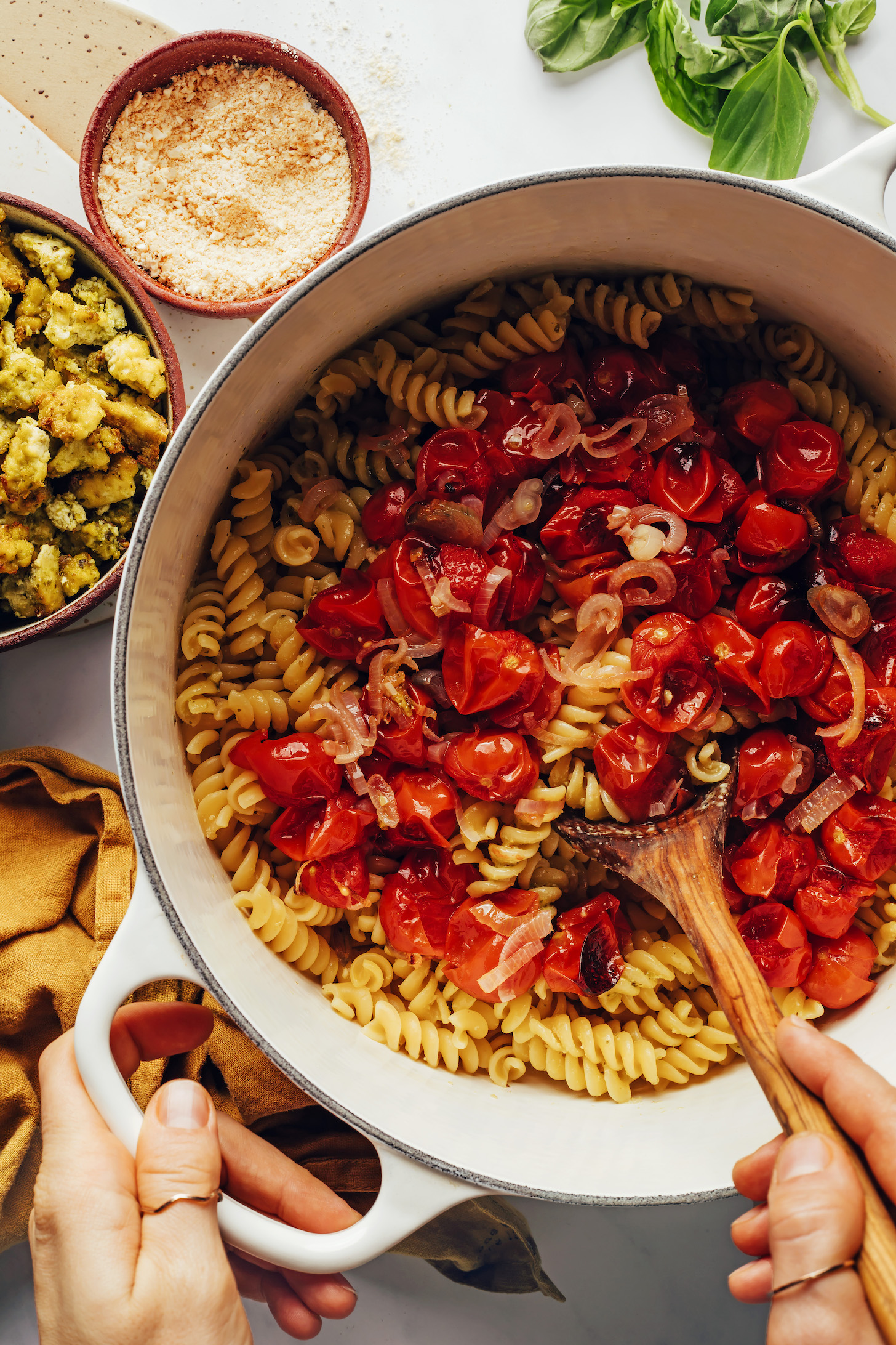 Stirring roasted tomatoes and shallots into cooked pasta