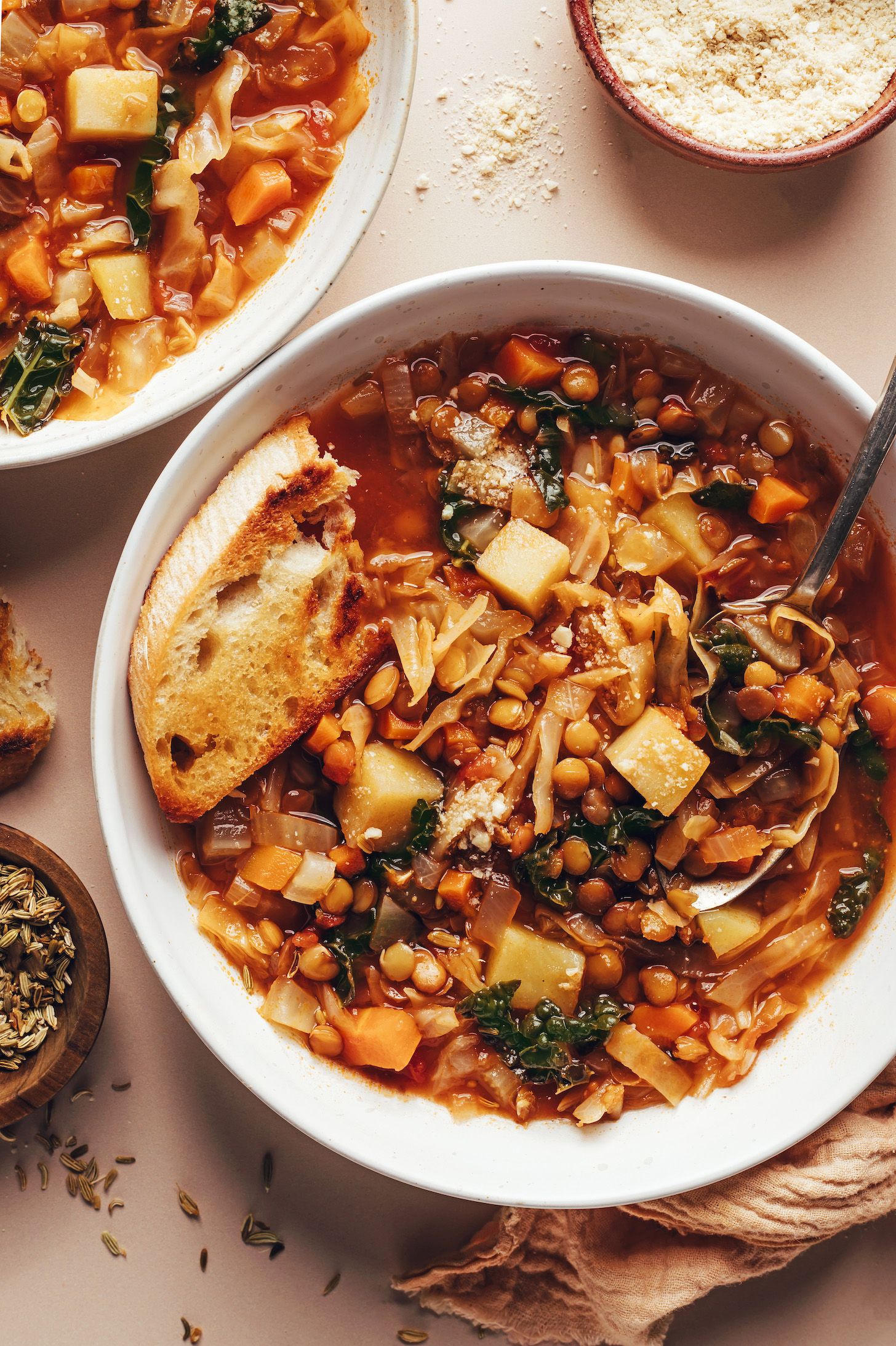 Toasted bread in a bowl of cabbage, fennel, lentil, and potato soup