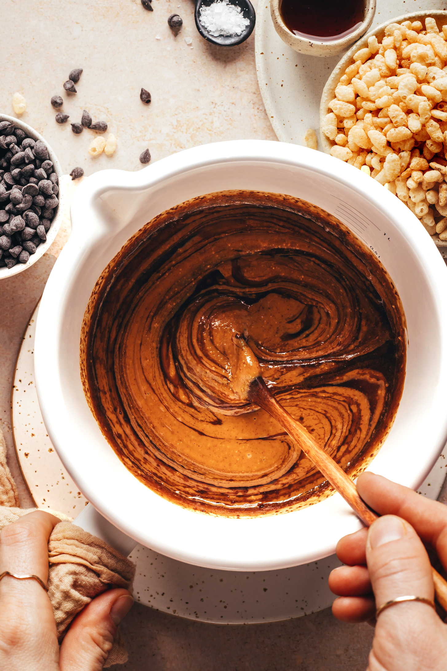Stirring together maple syrup, coconut sugar, peanut butter, and vanilla in a saucepan