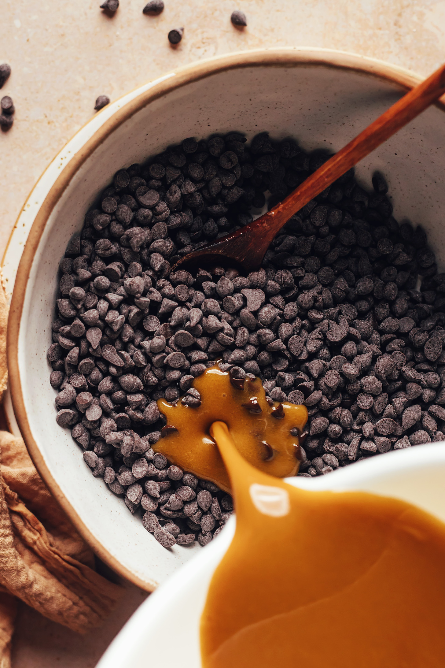 Pouring a melted vegan butter, coconut sugar, and coconut cream mixture over chocolate chips