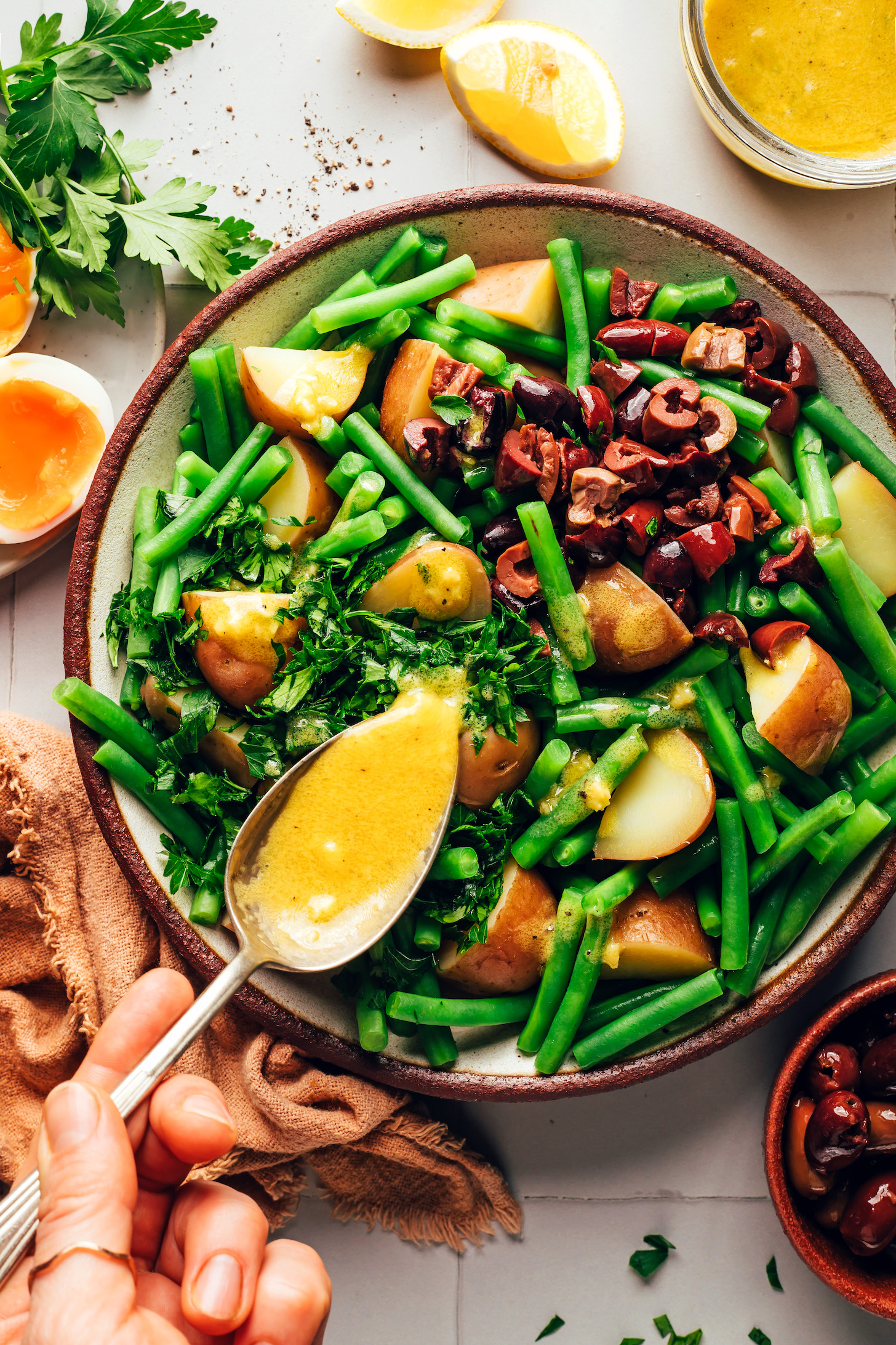 Using a spoon to drizzle a zippy mustard vinaigrette over a salad