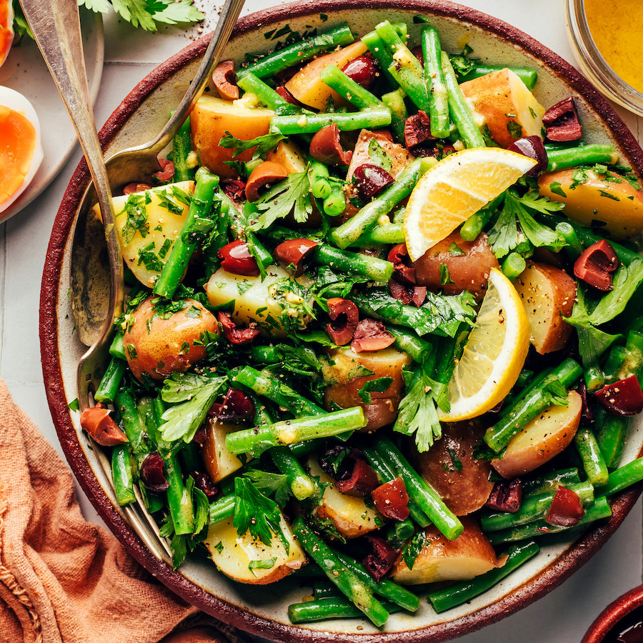 Overhead shot of two spoons in a bowl of French style green bean potato salad