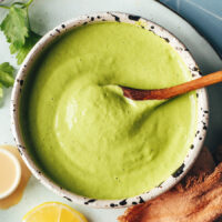 Overhead shot of a spoon in a bowl of herby green tahini sauce