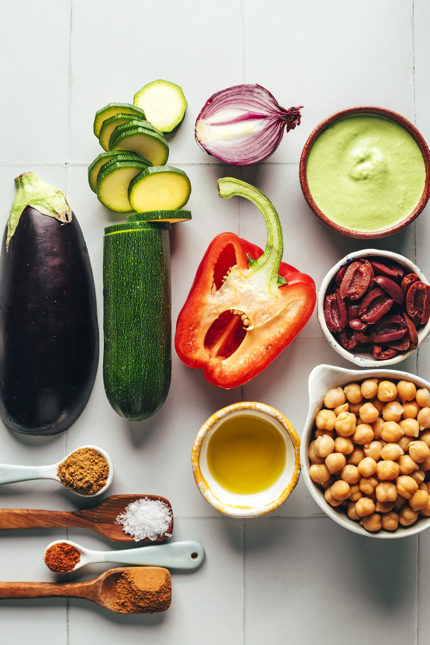 Eggplant, zucchini, red onion, red bell pepper, green tahini sauce, kalamata olives, chickpeas, olive oil, salt, cumin, cinnamon, and cayenne
