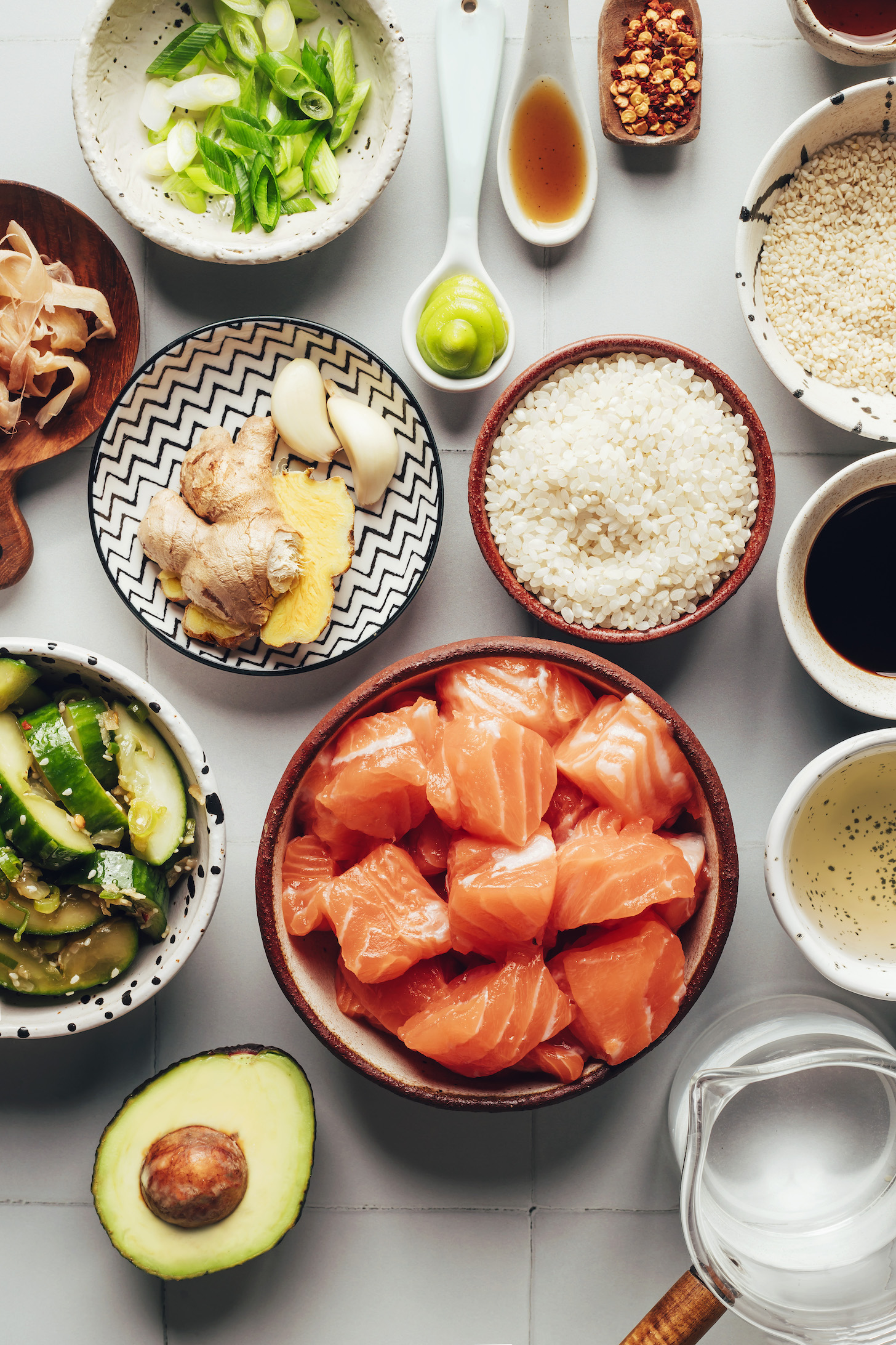 Green onion, pickled ginger, fresh ginger and garlic, cucumber salad, avocado, salmon, water, rice vinegar, tamari, and other ingredients for making salmon sushi bowls