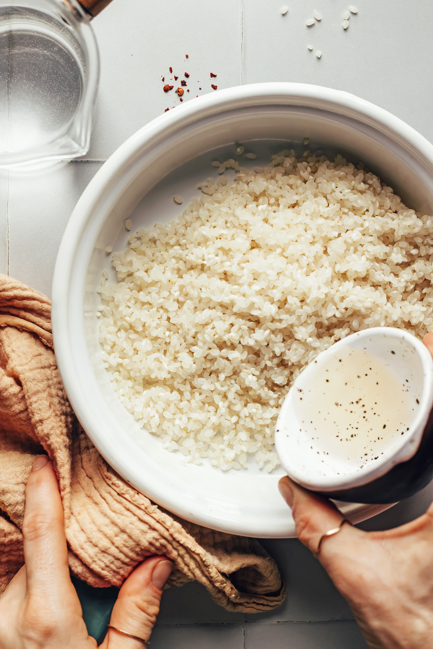 Pouring rice vinegar over a saucepan of sushi rice