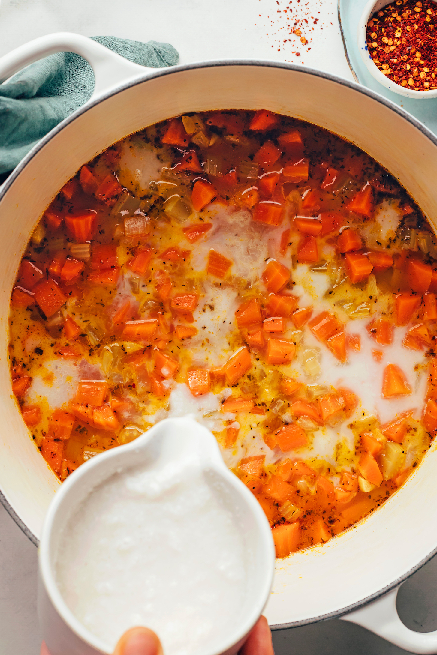 Pouring coconut milk into a pot of soup