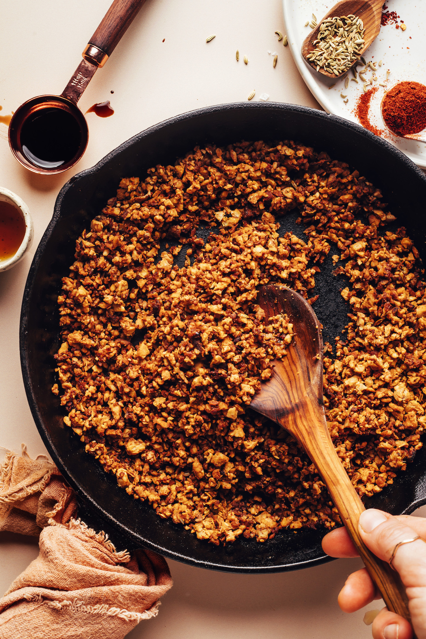 Stirring vegan crumbled tempeh sausage crumbles in a skillet