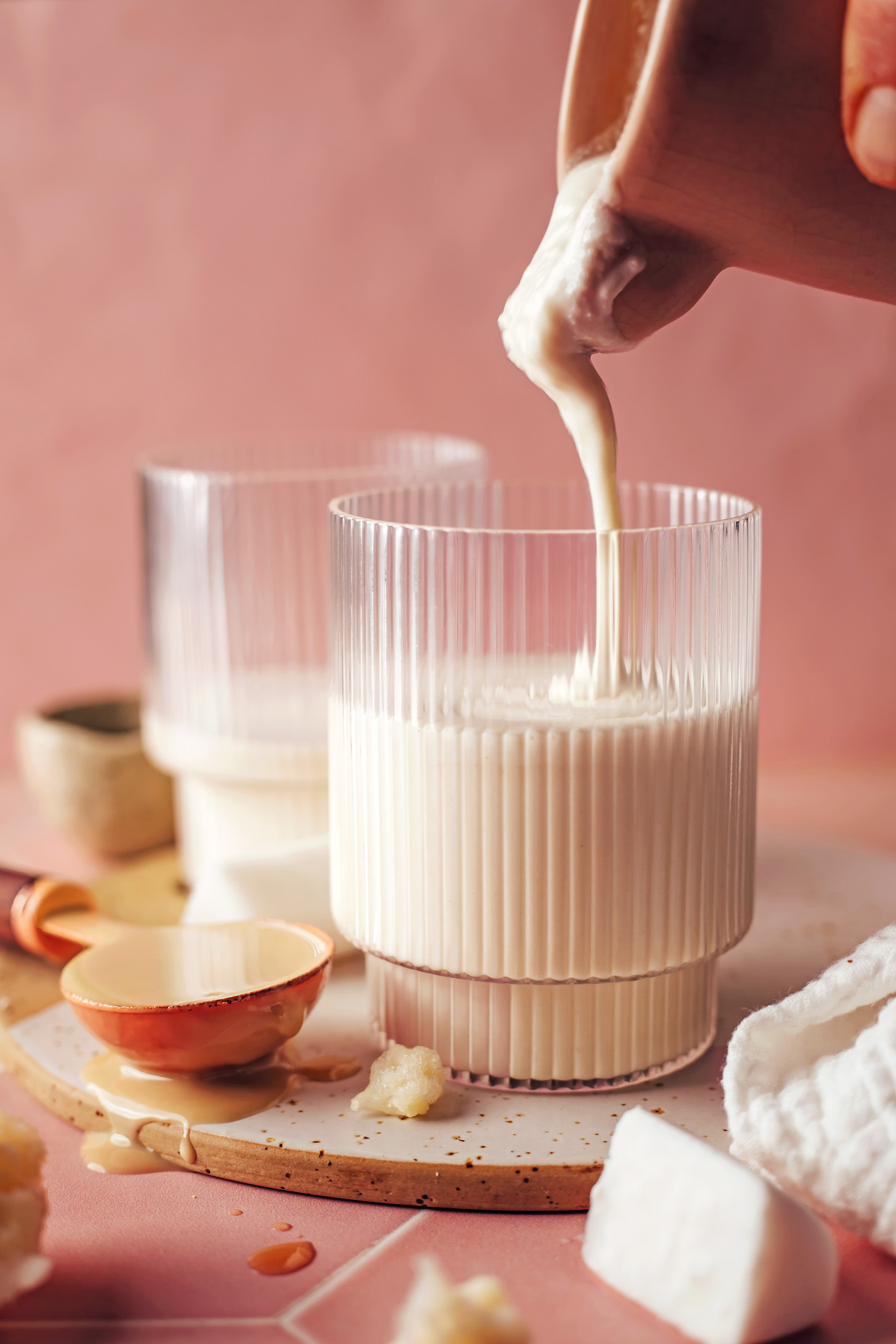 Pouring a vegan vanilla tahini shake into a glass
