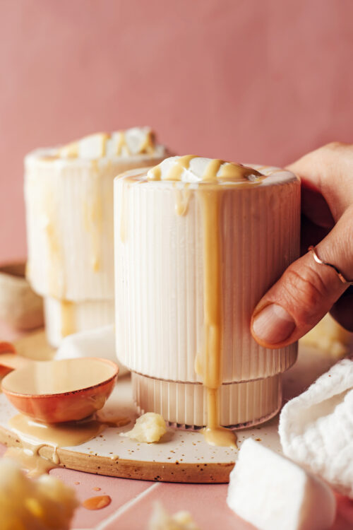 Holding the side of a glass of a vegan vanilla milkshake dripping with tahini