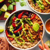 Drizzling aji verde sauce over a smashed chickpea taco bowl