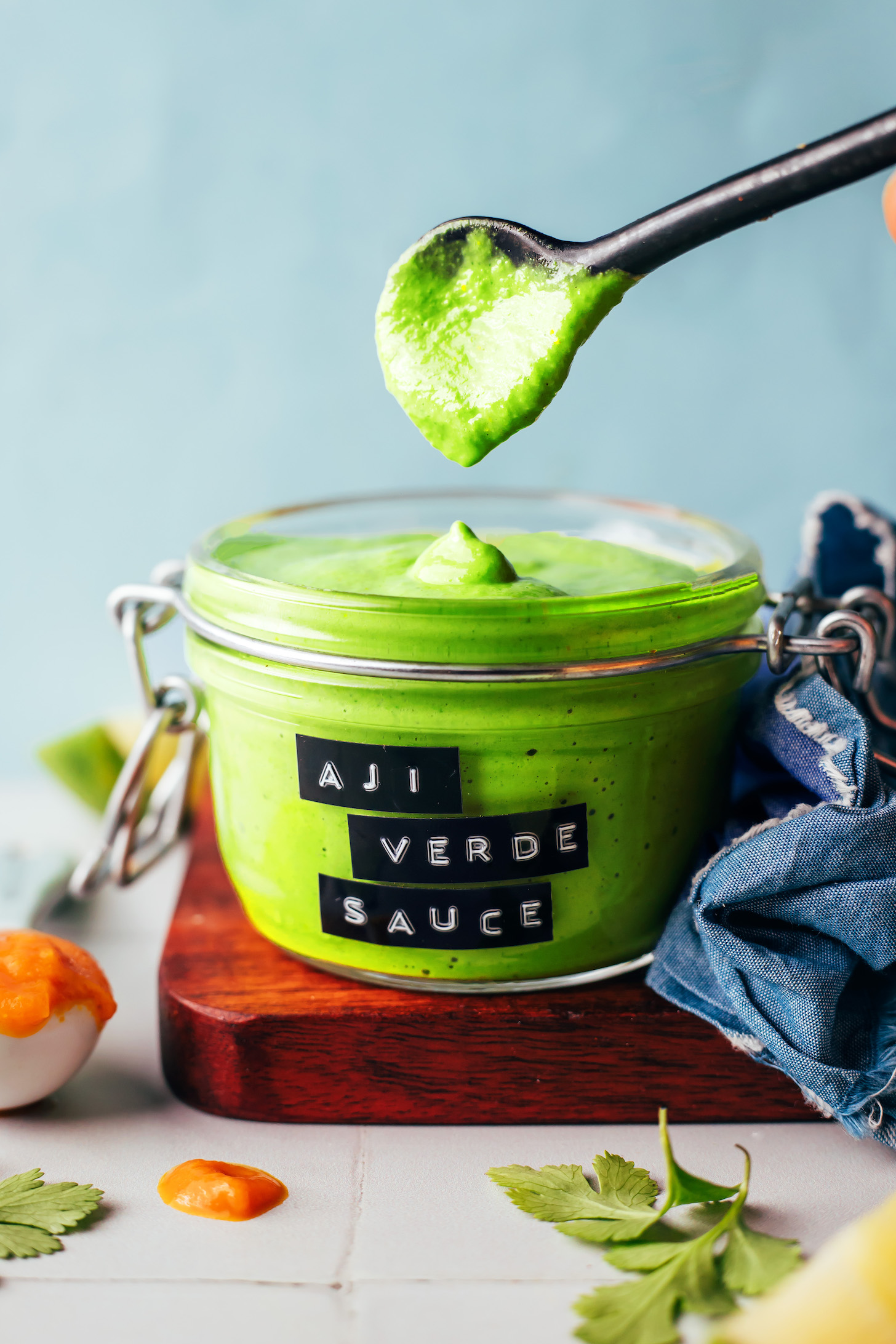 Thick, creamy aji verde sauce dripping from a spoon into a jar