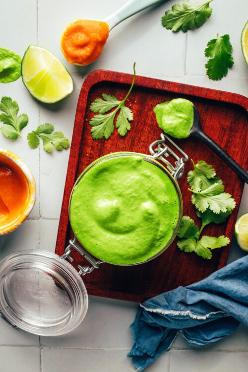 Overhead shot of a jar of vegan aji verde sauce surrounded by ingredients used to make it