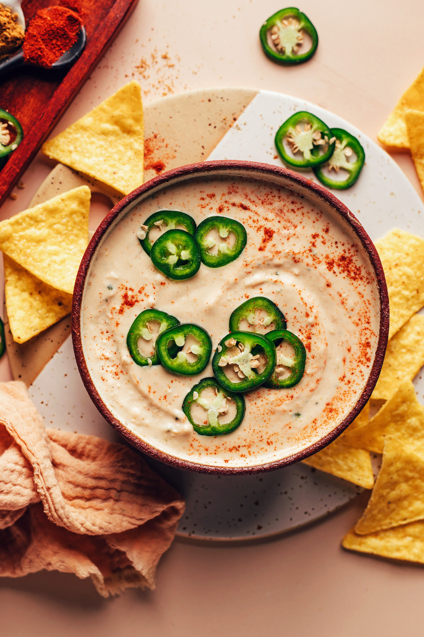 Bowl of vegan white bean dip topped with sliced jalapeños and smoked paprika
