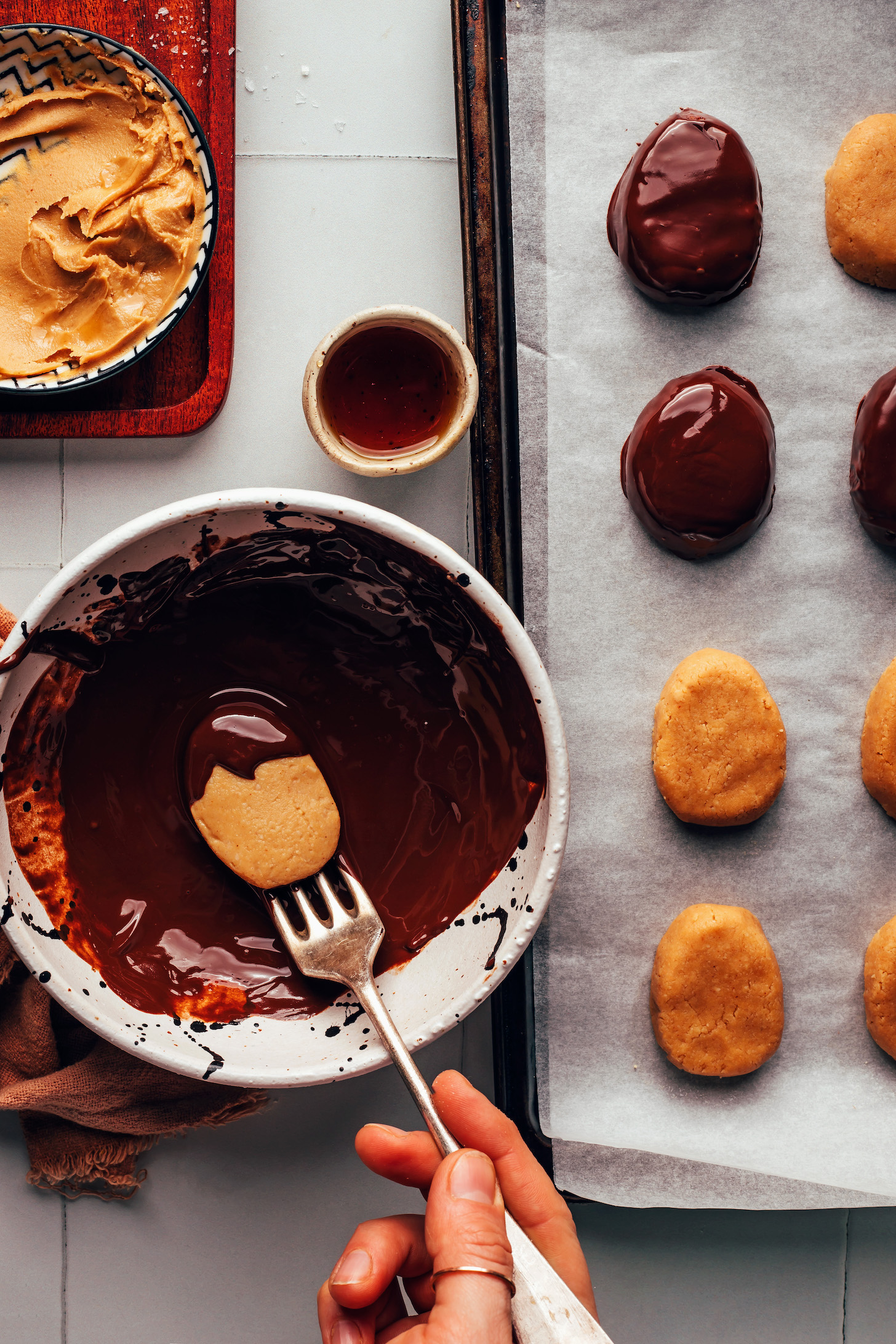 Dipping an oval-shaped peanut butter mixture into a bowl of melted chocolate