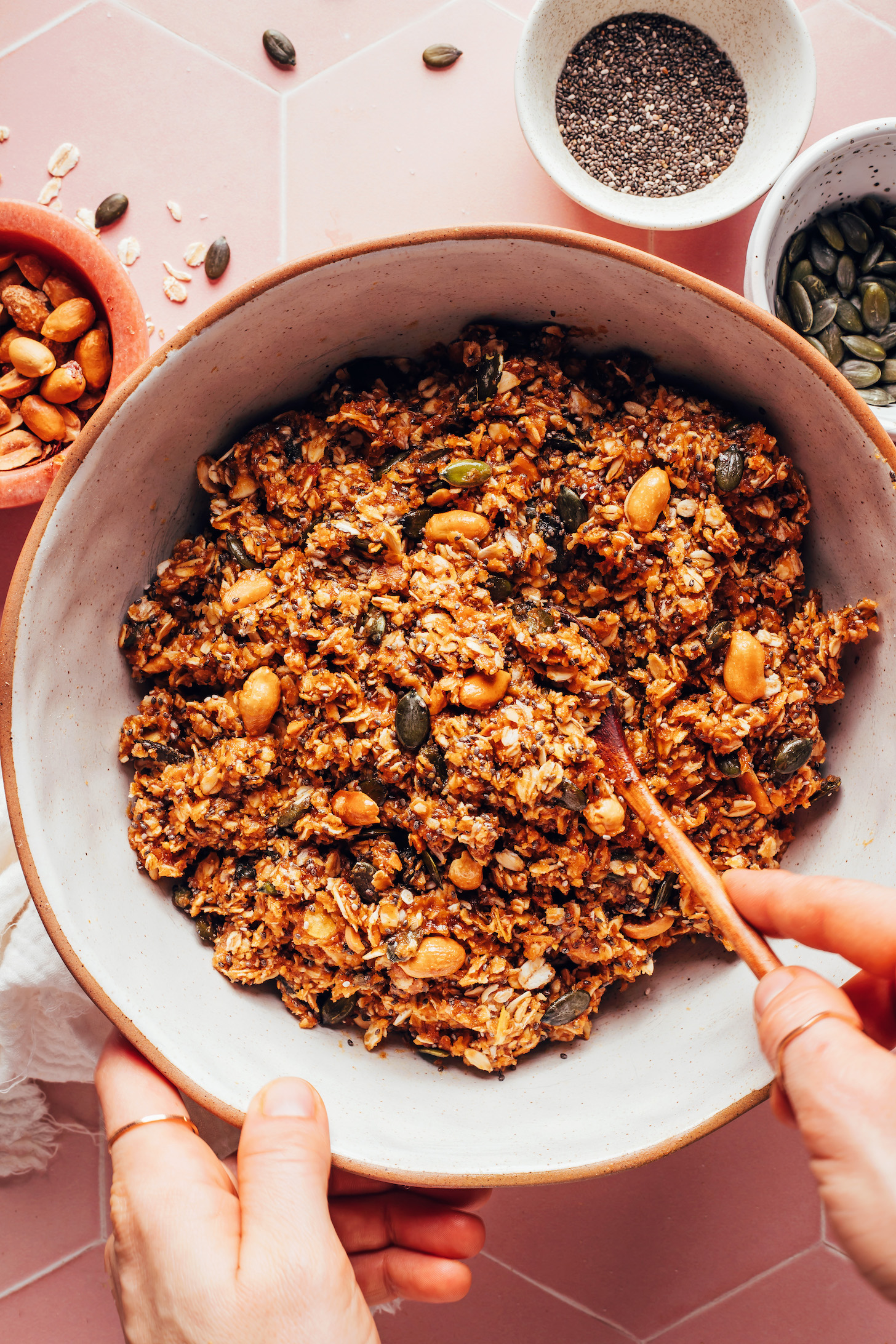 Stirring together oats, peanuts, and other ingredients to make peanut butter cookie granola