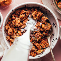 Overhead shot of pouring granola over a bowl of peanut butter granola