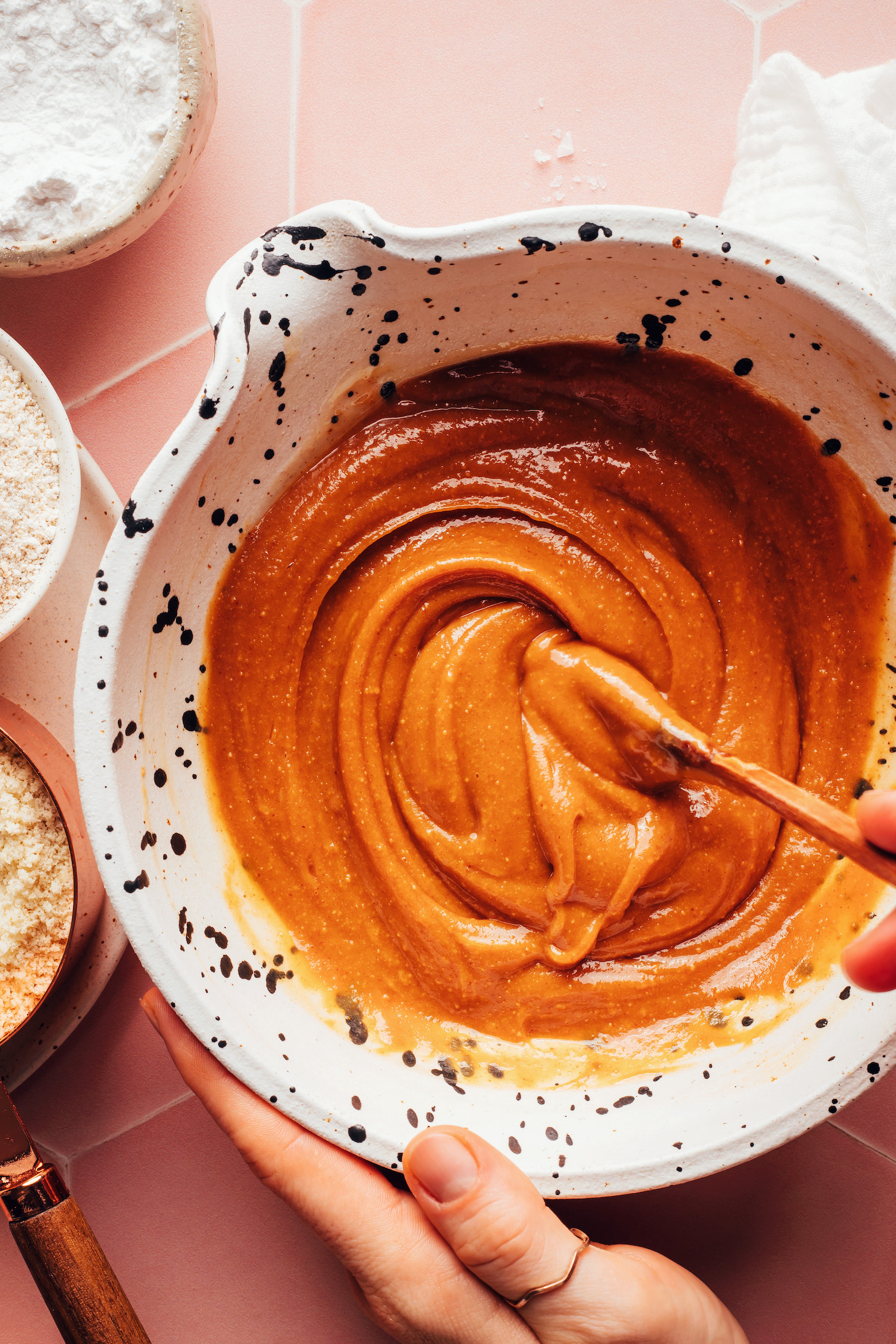 Stirring peanut butter, maple syrup, coconut oil, baking soda, and sea salt in a mixing bowl