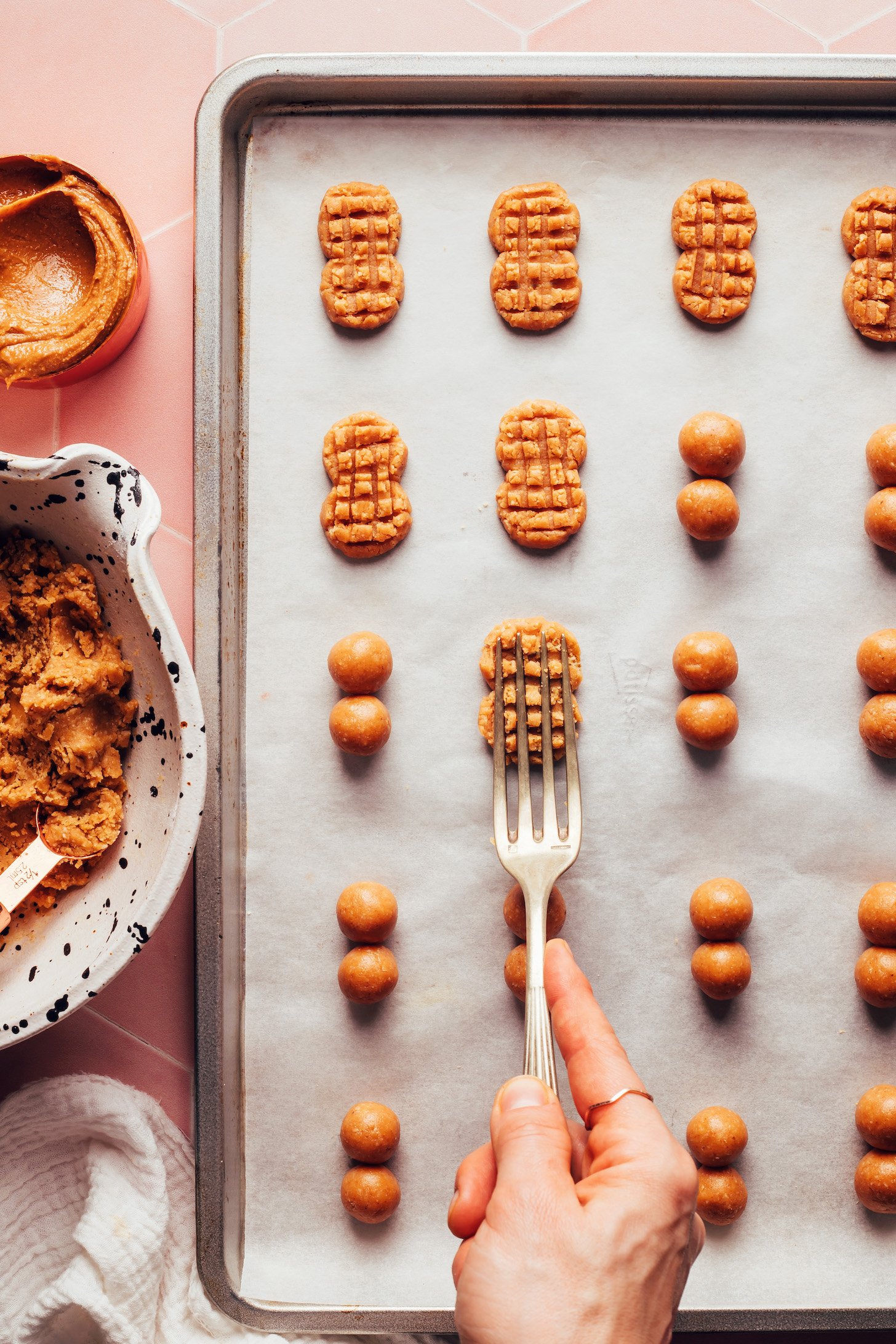 Pressing the back of a fork into a peanut butter cookie to make a classic nutter butter look