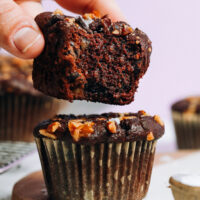 Holding a partially eaten salted chocolate banana nut muffin above another muffin