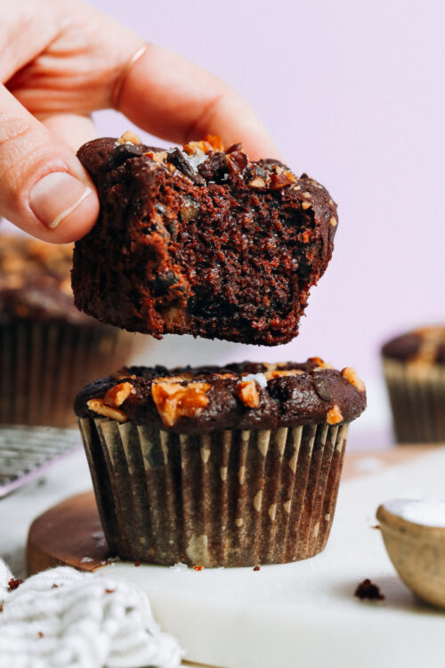Holding a partially eaten salted chocolate banana nut muffin above another muffin