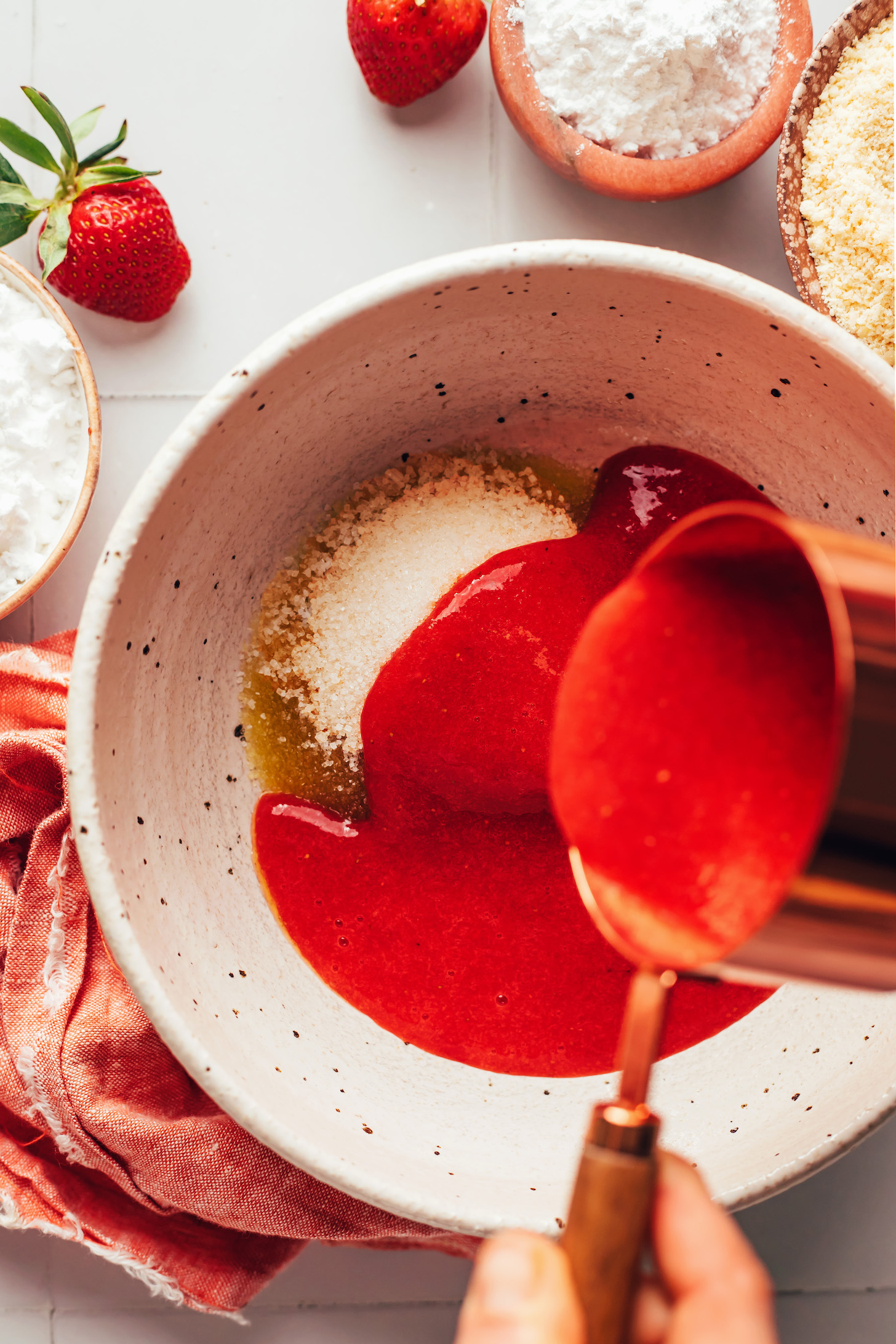Pouring fresh strawberry purée into a bowl with the other wet ingredients