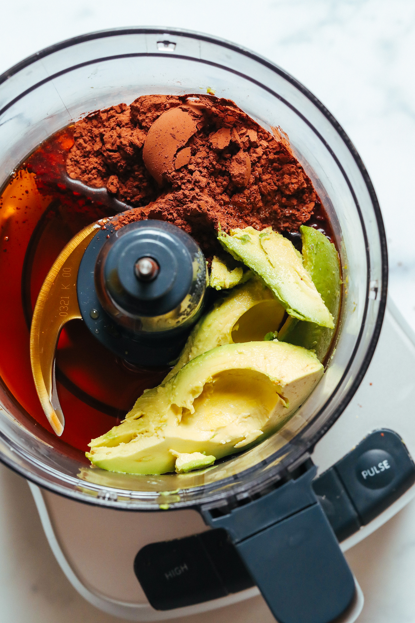 Food processor with avocado, salt, cocoa powder, maple syrup, and vanilla