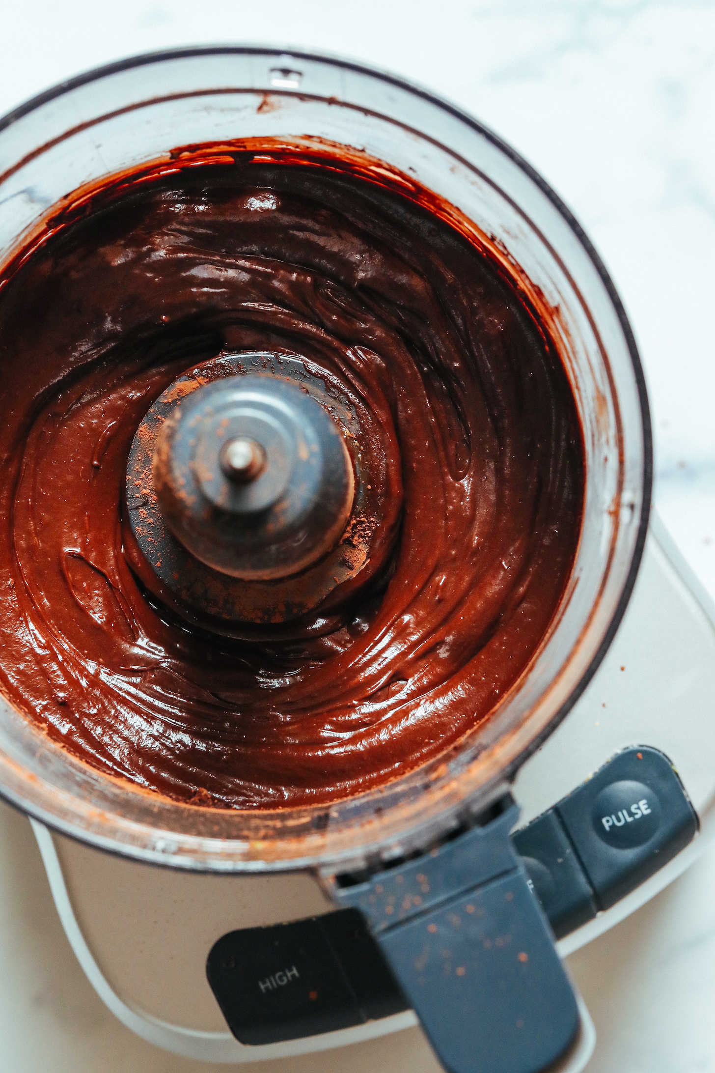 Food processor filled with creamy, pudding-like frosting made without powdered sugar