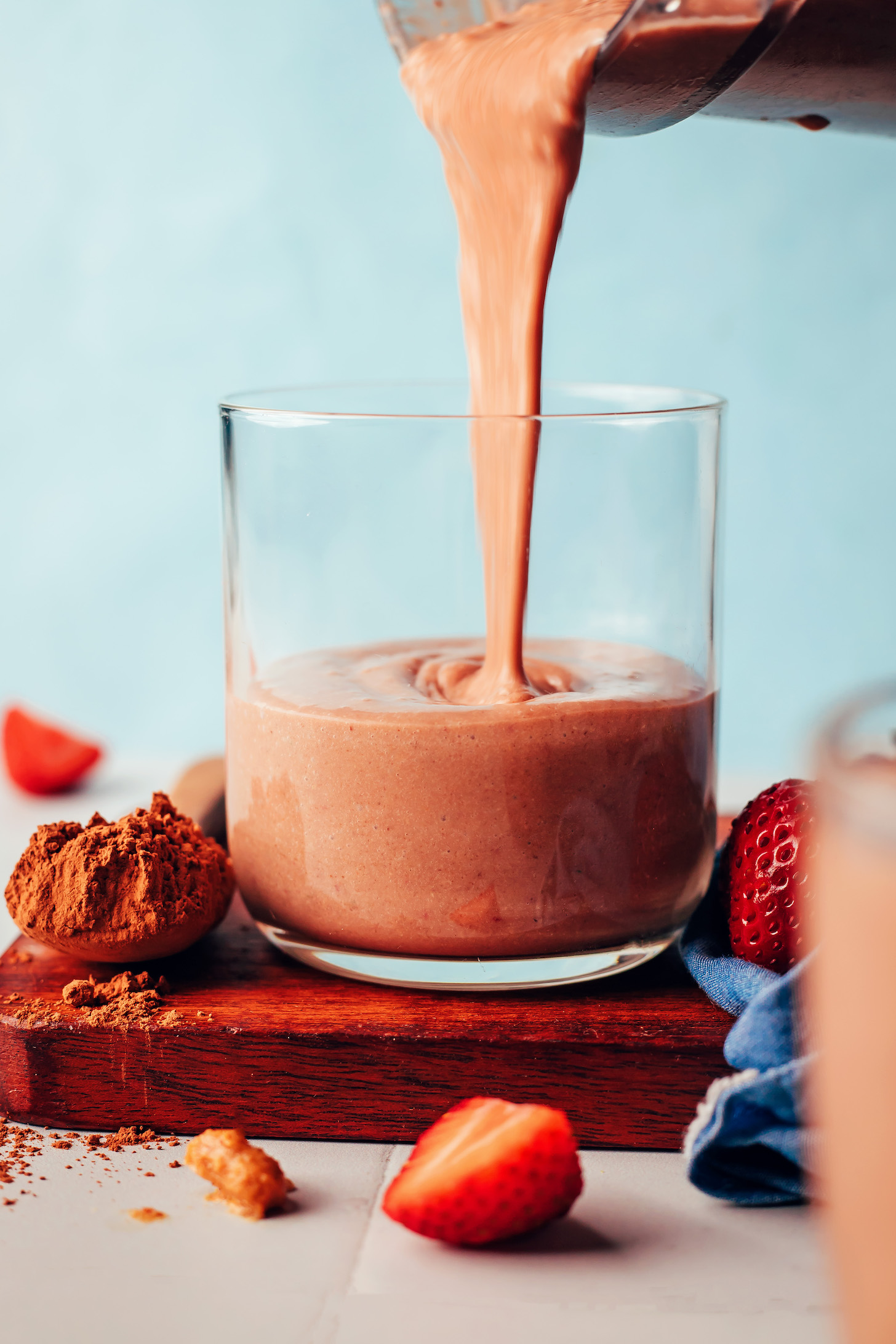 Pouring a creamy vegan chocolate smoothie into a glass