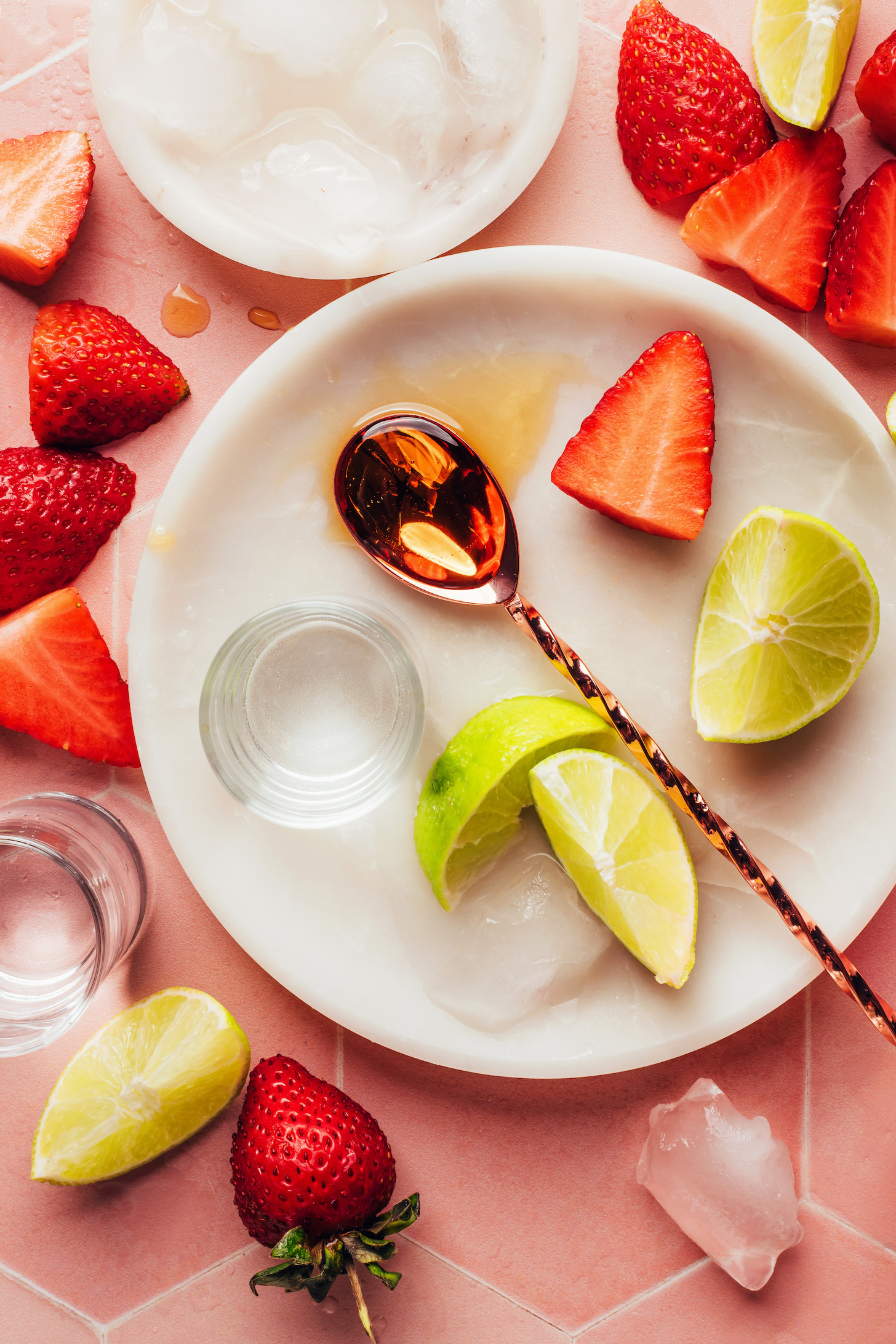 Ice, strawberries, lime wedges, maple syrup, and tequila