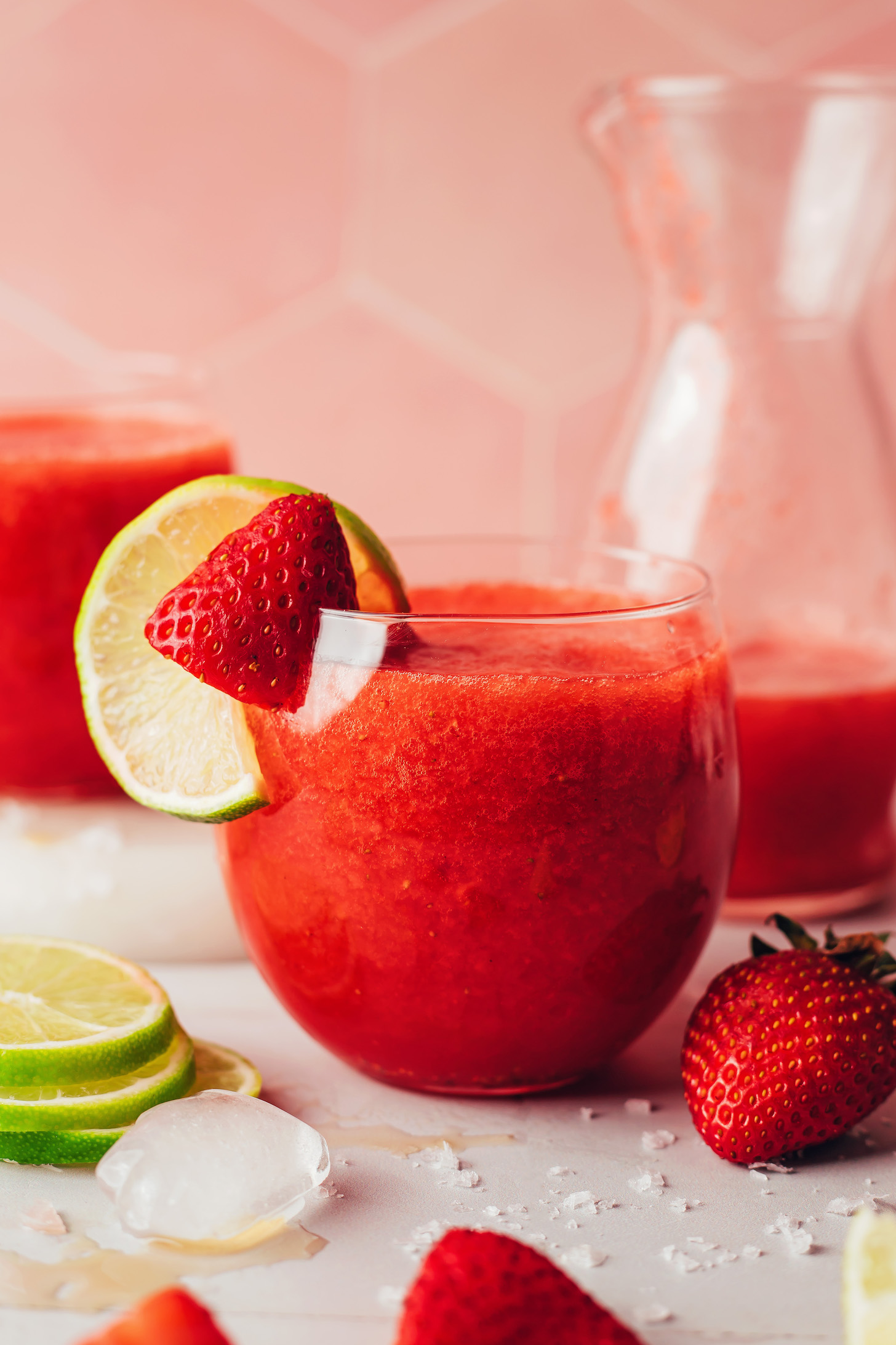 Strawberry margarita served straight up in a glass with strawberry and lime slices on the rim