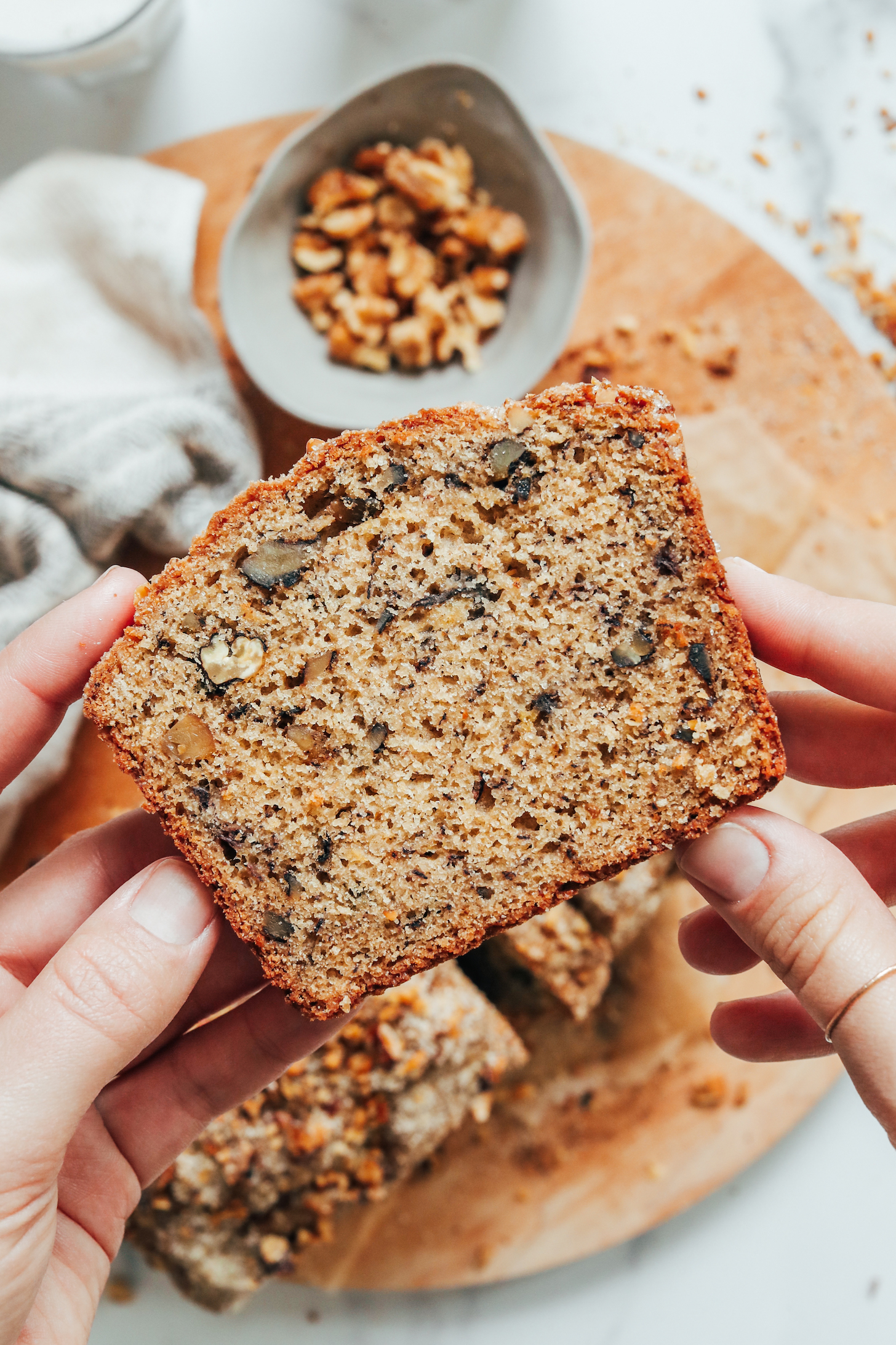 Hands holding a slice of banana walnut bread to show the texture