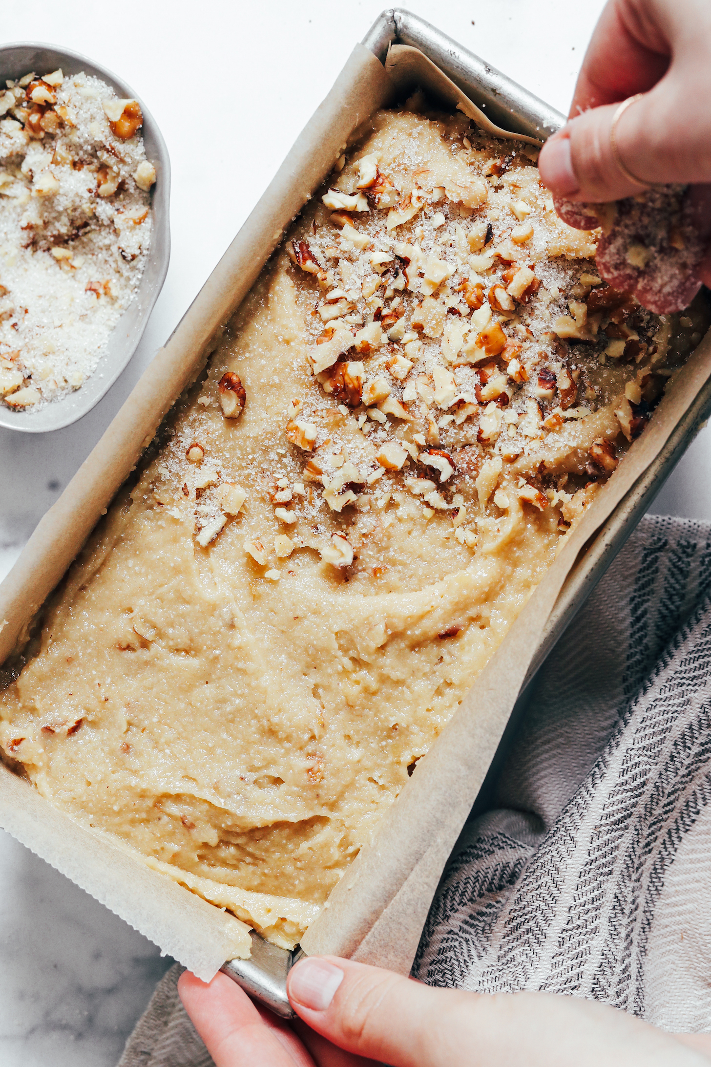 Sprinkling chopped pecans and cane sugar over the loaf